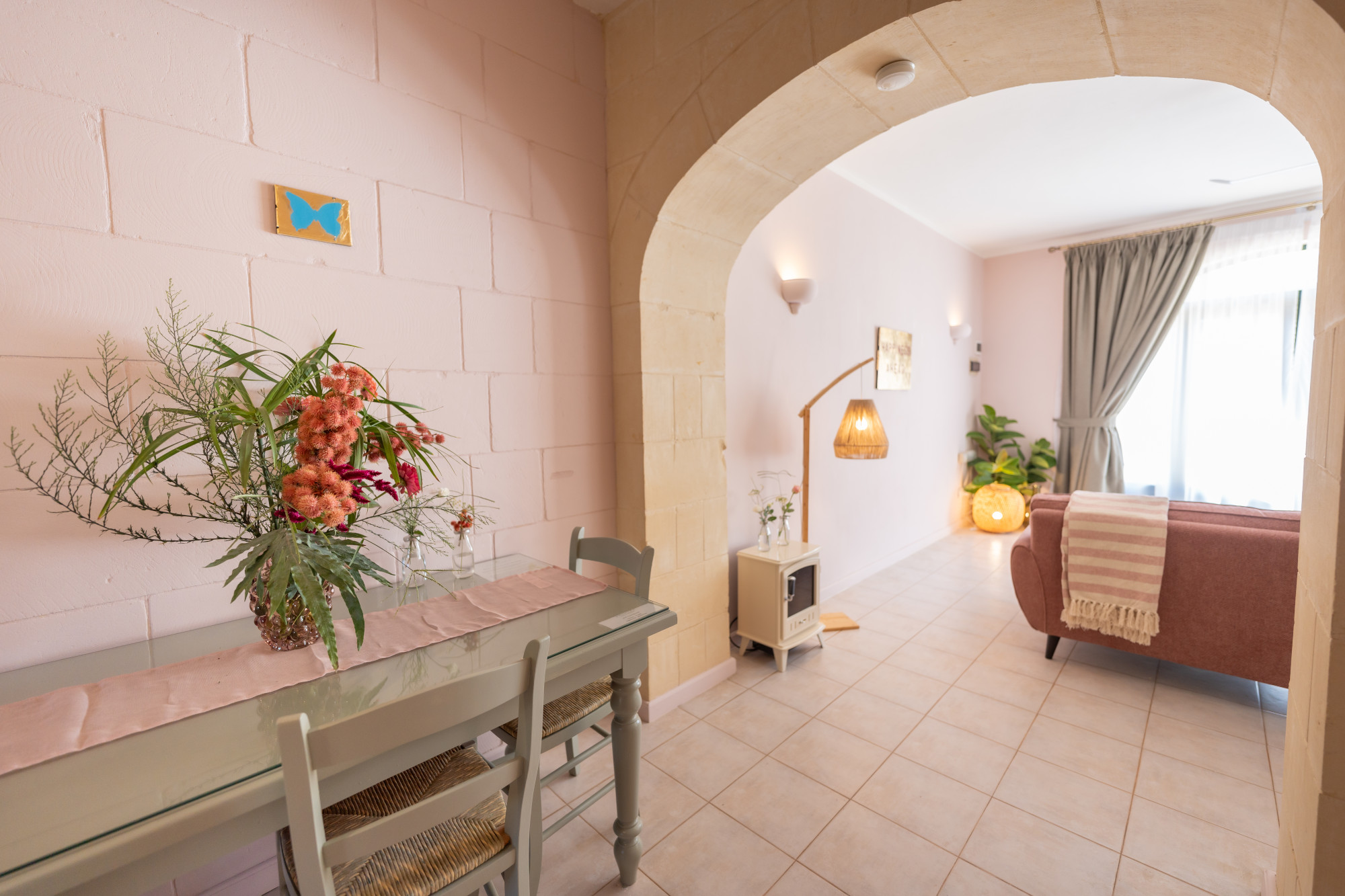 Dining area with fresh flowers and limestone archway into the living room