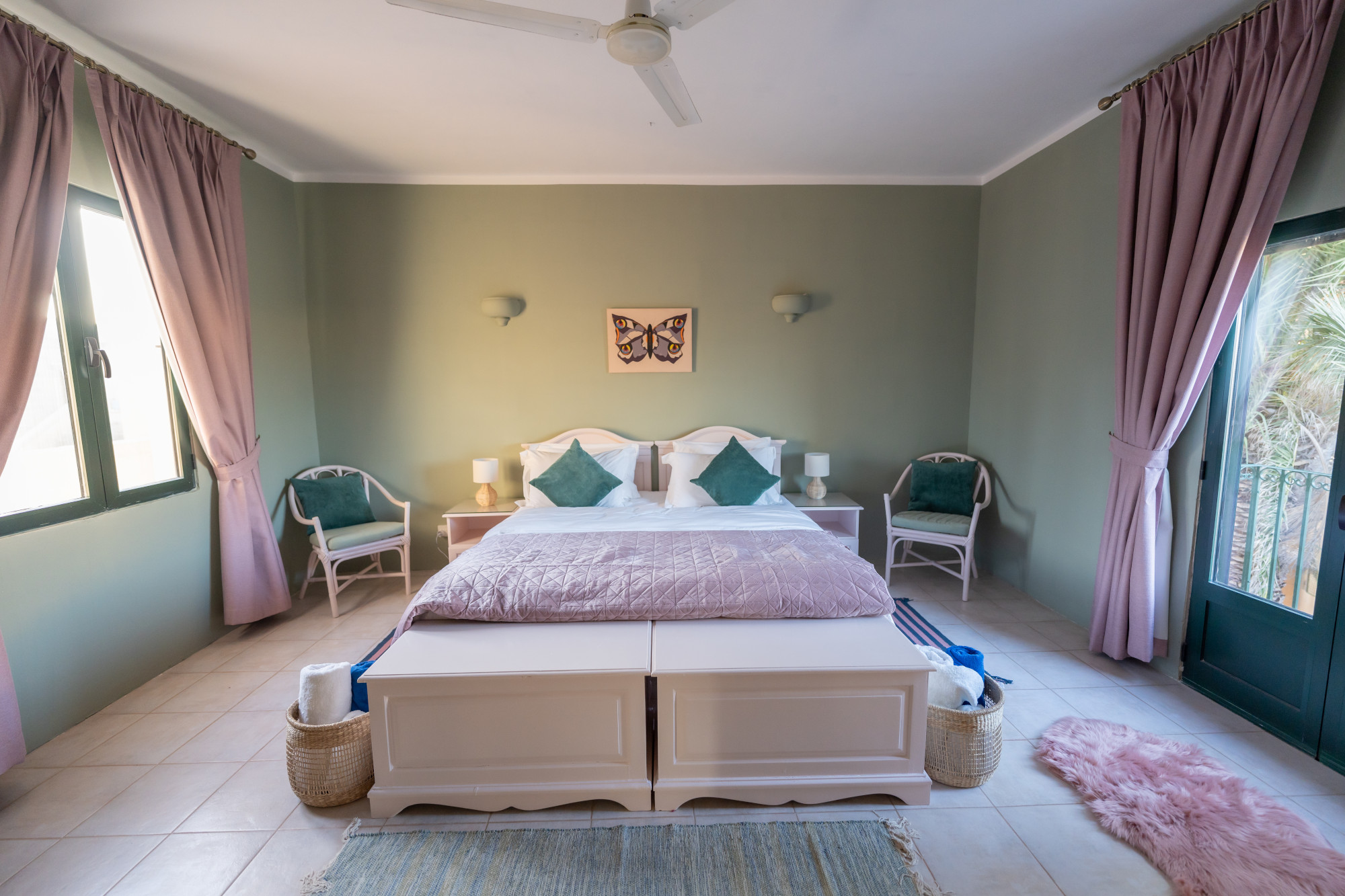 Peaceful bedroom suite with soft sage walls, balcony access and plush furnishings