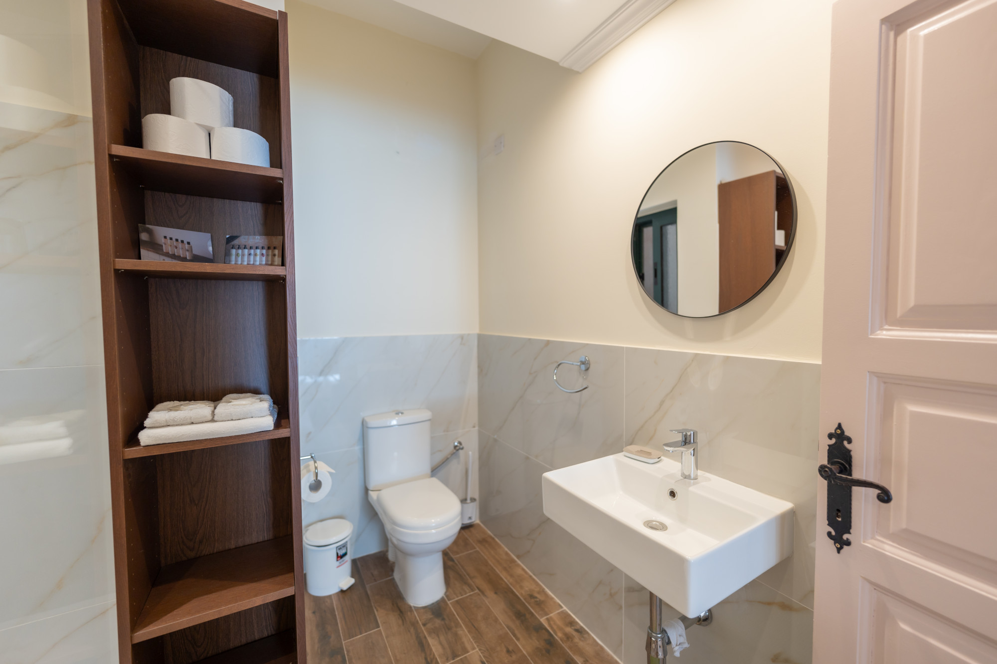 Modern en-suite bathroom with marble tiling and circular mirror