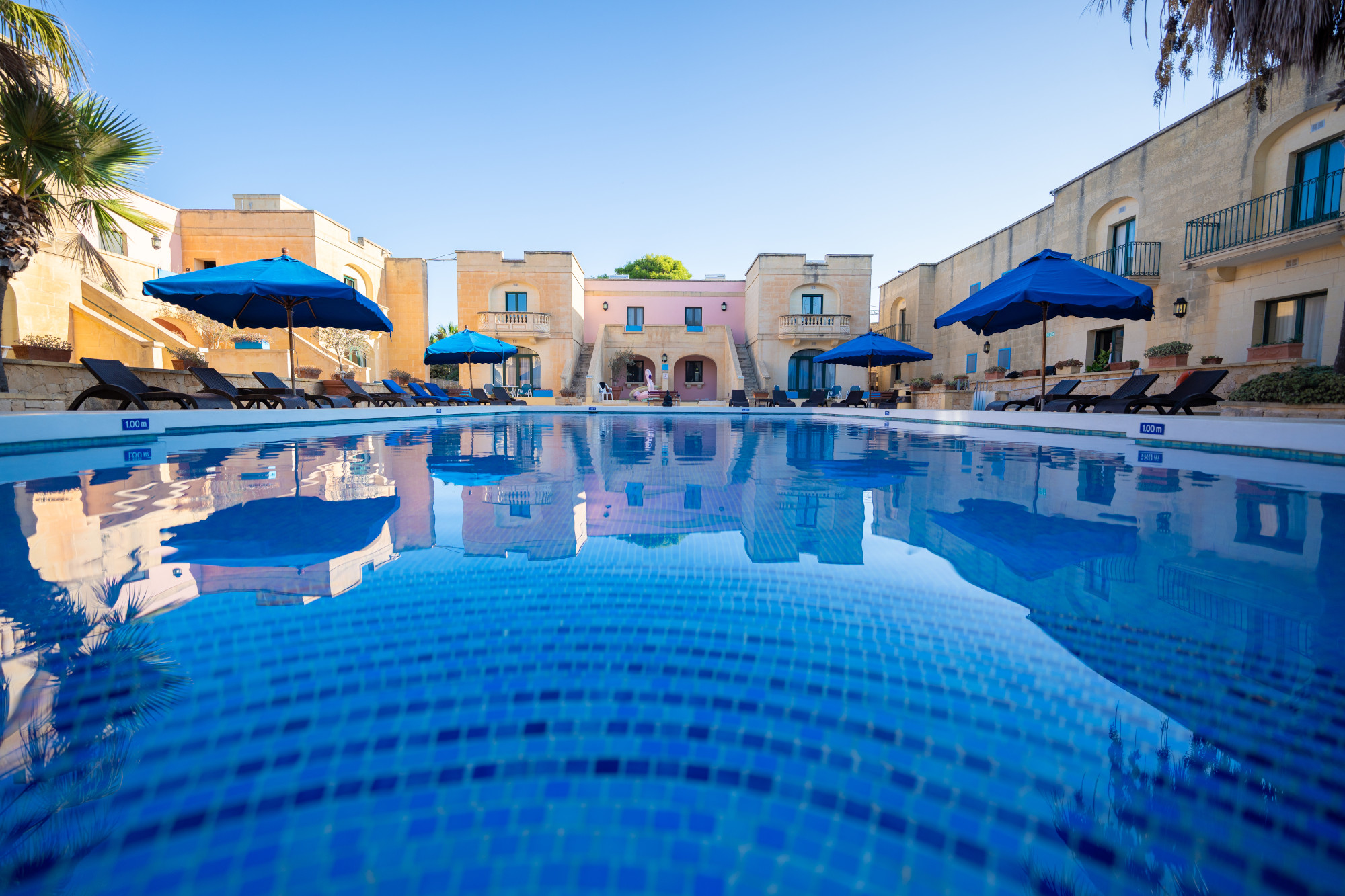 Courtyard swimming pool and sun loungers with blue parasols