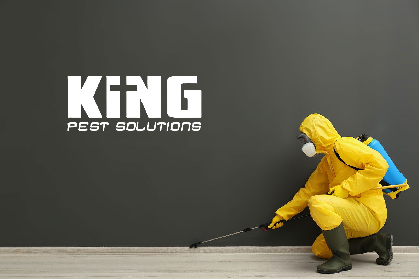 King Pest Solutions technician spraying pest control treatment against a wall
