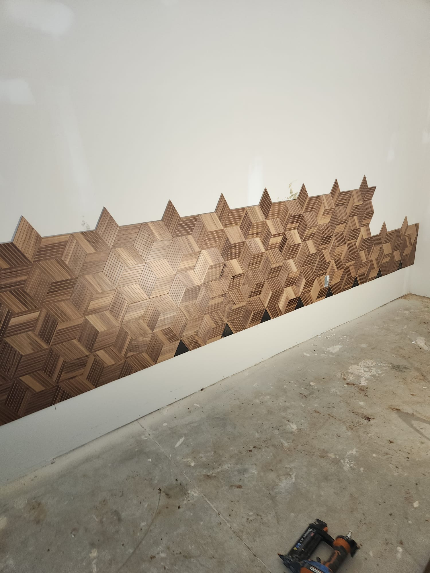 Handcrafted 3D geometric wooden mosaic accent wall under construction with finish nailer in Greensboro NC