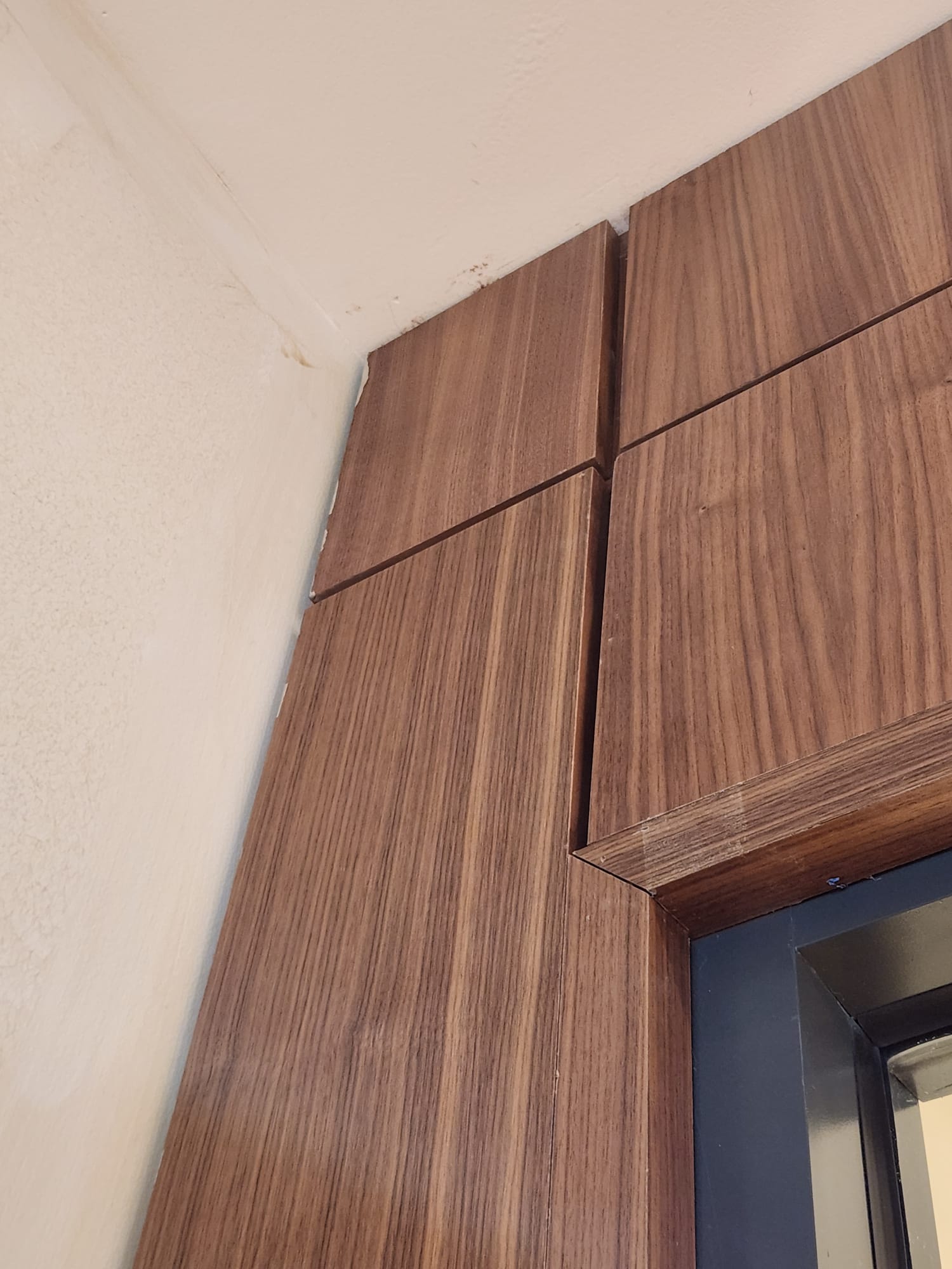 Precision walnut wood paneling corner reveal joint and metal door casing intersection in Winston-Salem NC