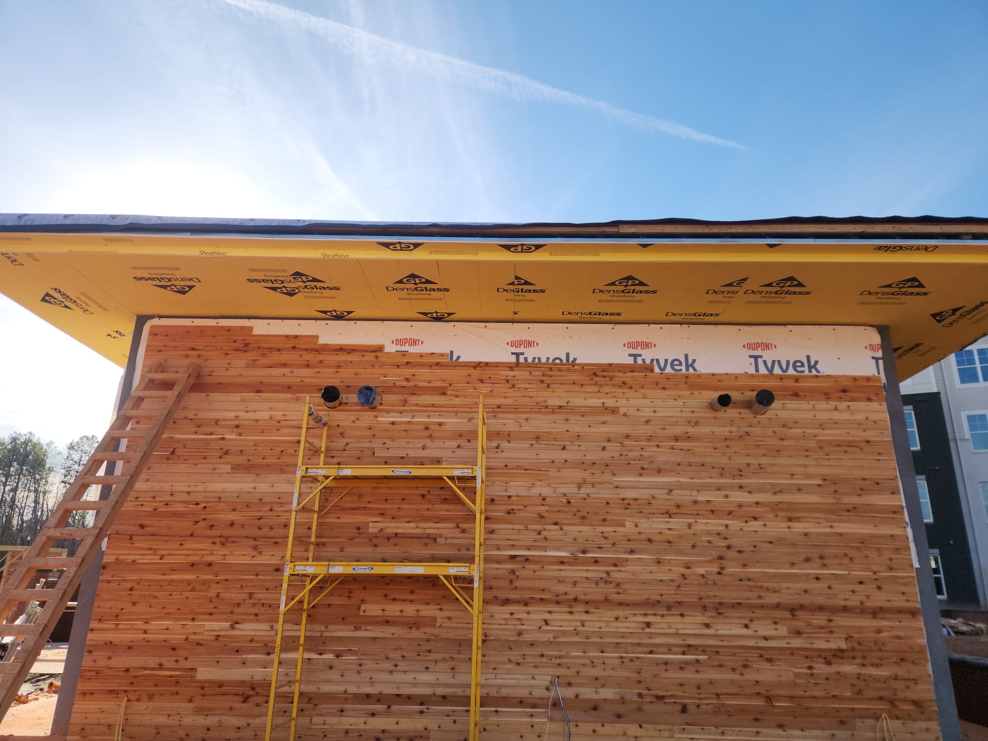 Exterior horizontal tongue and groove natural cedar timber siding and soffit installation on scaffolding in Winston-Salem NC