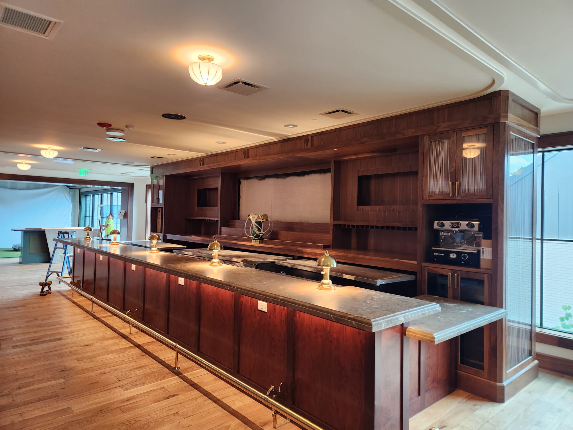 Full-scale custom rich walnut back bar, fluted glass cabinets, under-counter LED lights, and hardwood flooring in Winston-Salem NC