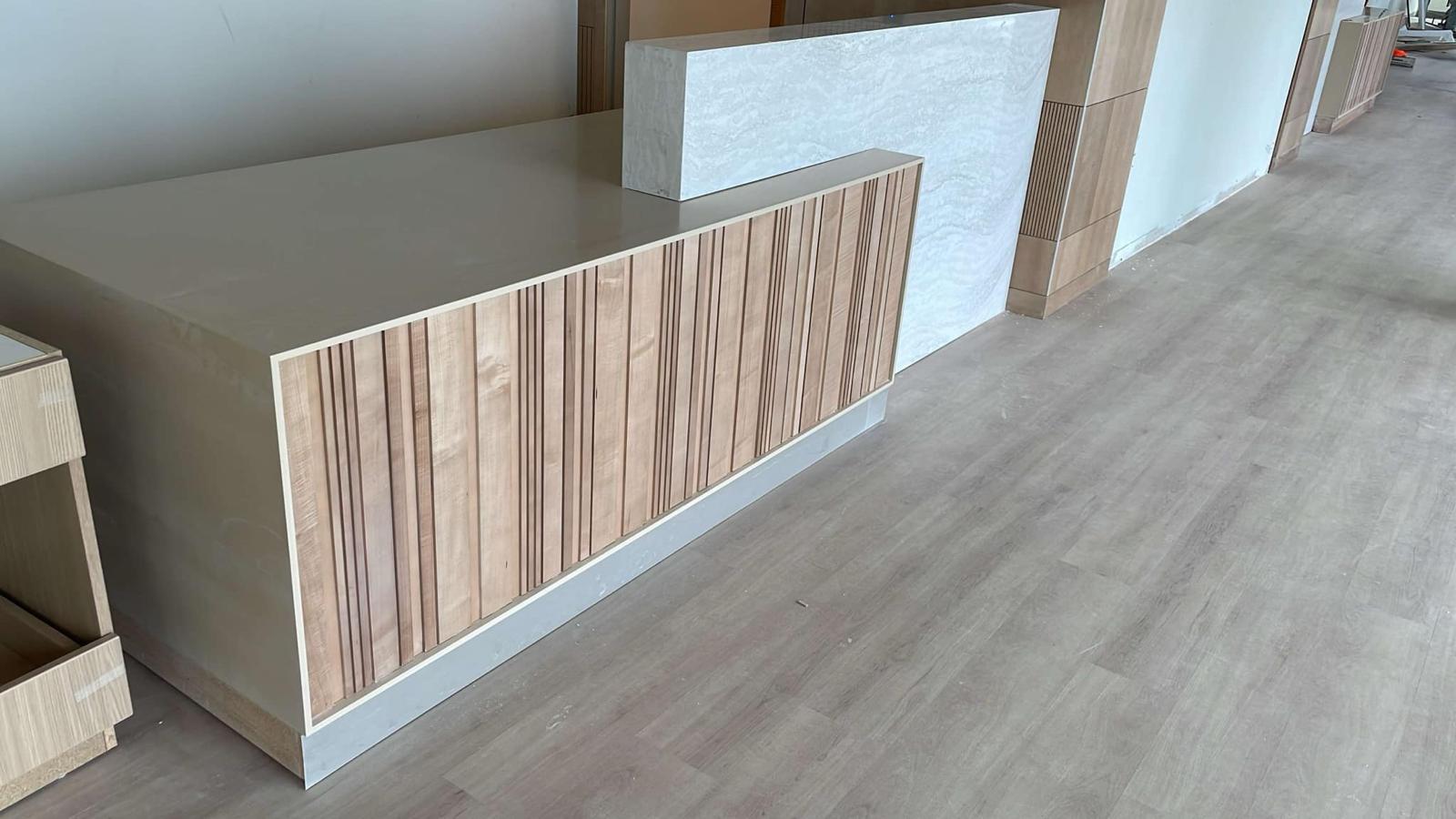 Custom crafted reception desk with natural fluted wood slats and stone transaction counter