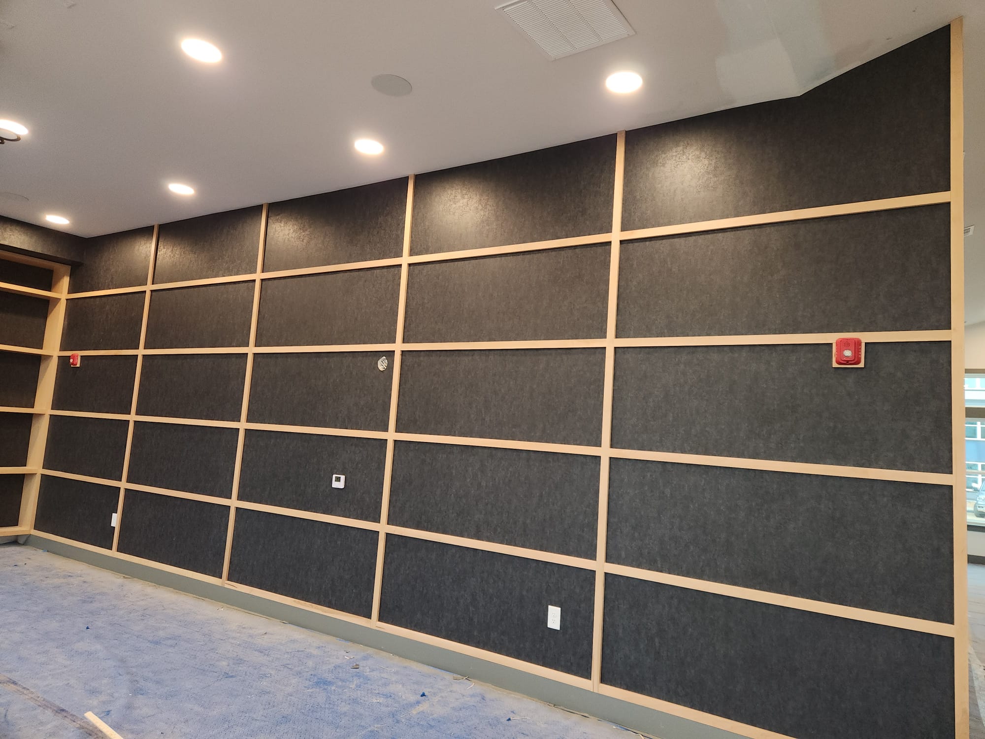Full-height charcoal texture wall panels with natural maple grid batten framing installed in Winston-Salem NC