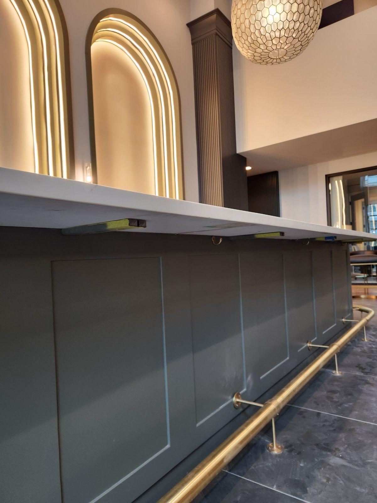 Custom paneled commercial bar front with marble countertop and brass foot rail in Winston-Salem NC