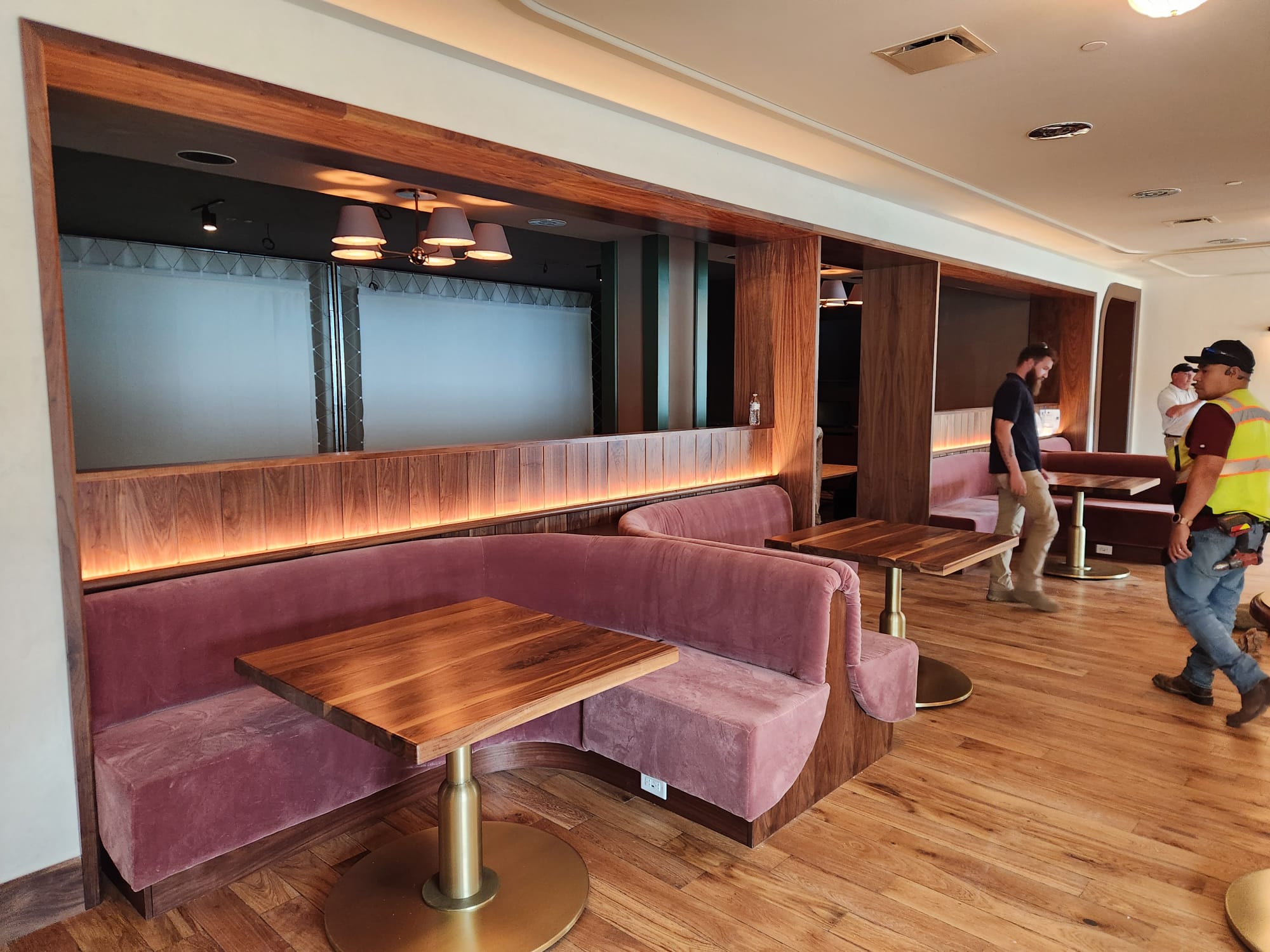 Grand dining room with walnut-clad booth niches, curved banquette seating, solid wood tables, and hardwood flooring in Winston-Salem NC