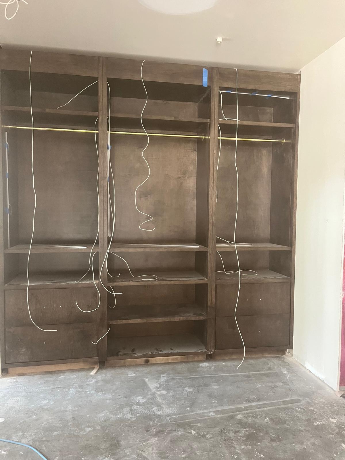 Custom rich hardwood 3-bay built-in wardrobe closet with brass hanging rods in Clemmons NC