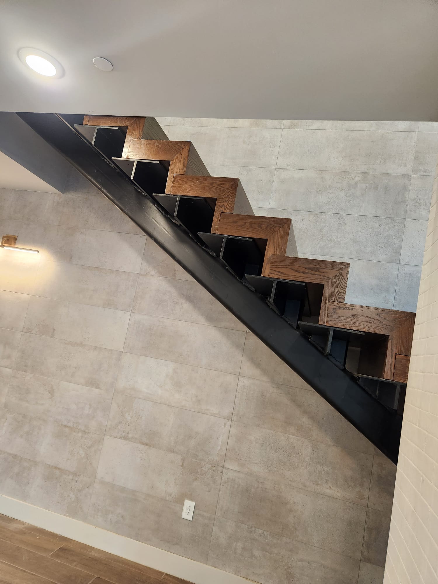 Underside view of structural steel beam staircase with custom wrap-around oak treads in Lewisville NC