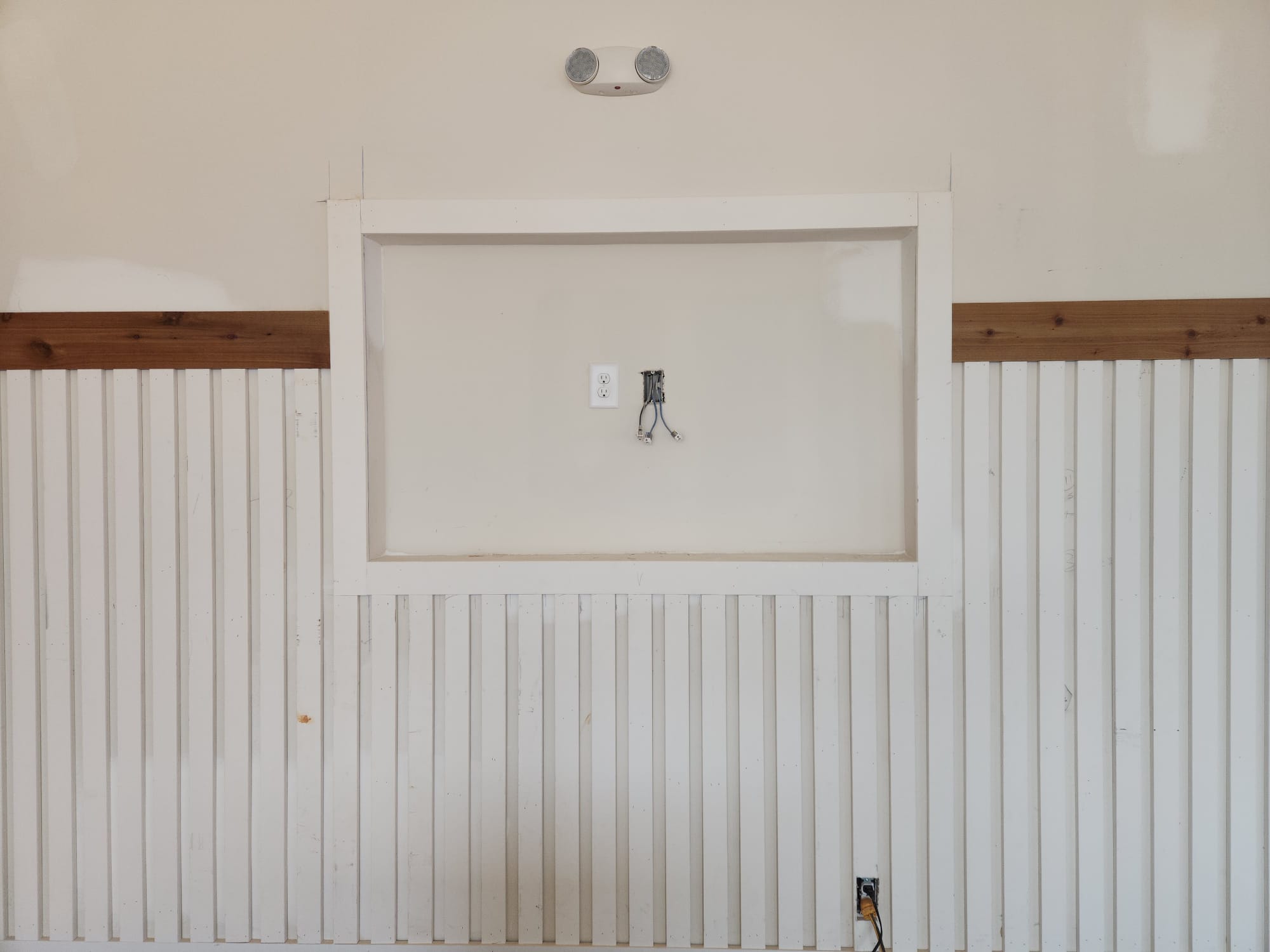 Vertical slat wainscoting with hardwood accent cap rail and cased wall niche under construction in Greensboro NC