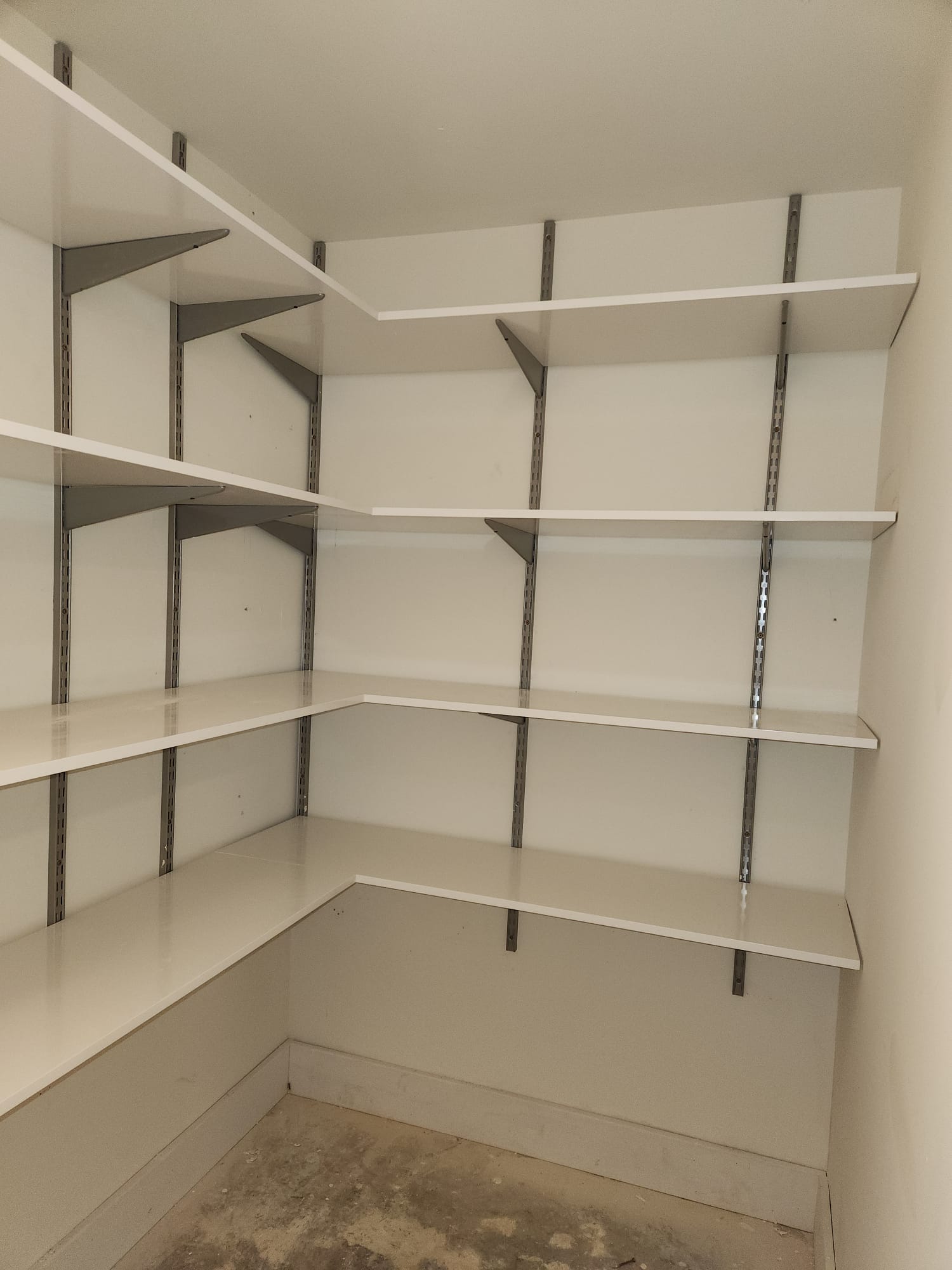 Multi-tier white corner pantry wrap-around shelving installation with heavy-duty adjustable brackets in Clemmons NC