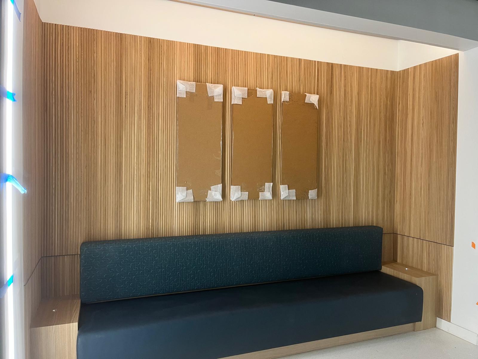 Natural vertical oak slat acoustic wall niche with upholstered built-in banquette bench in Winston-Salem NC