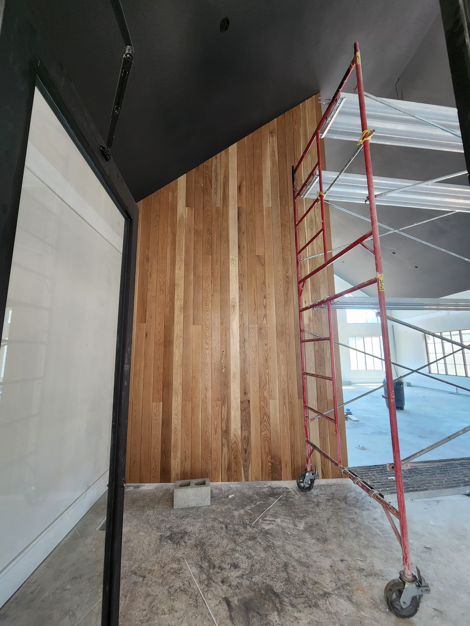 Floor to ceiling angled vaulted wall with vertical natural oak plank cladding under construction in Lewisville NC