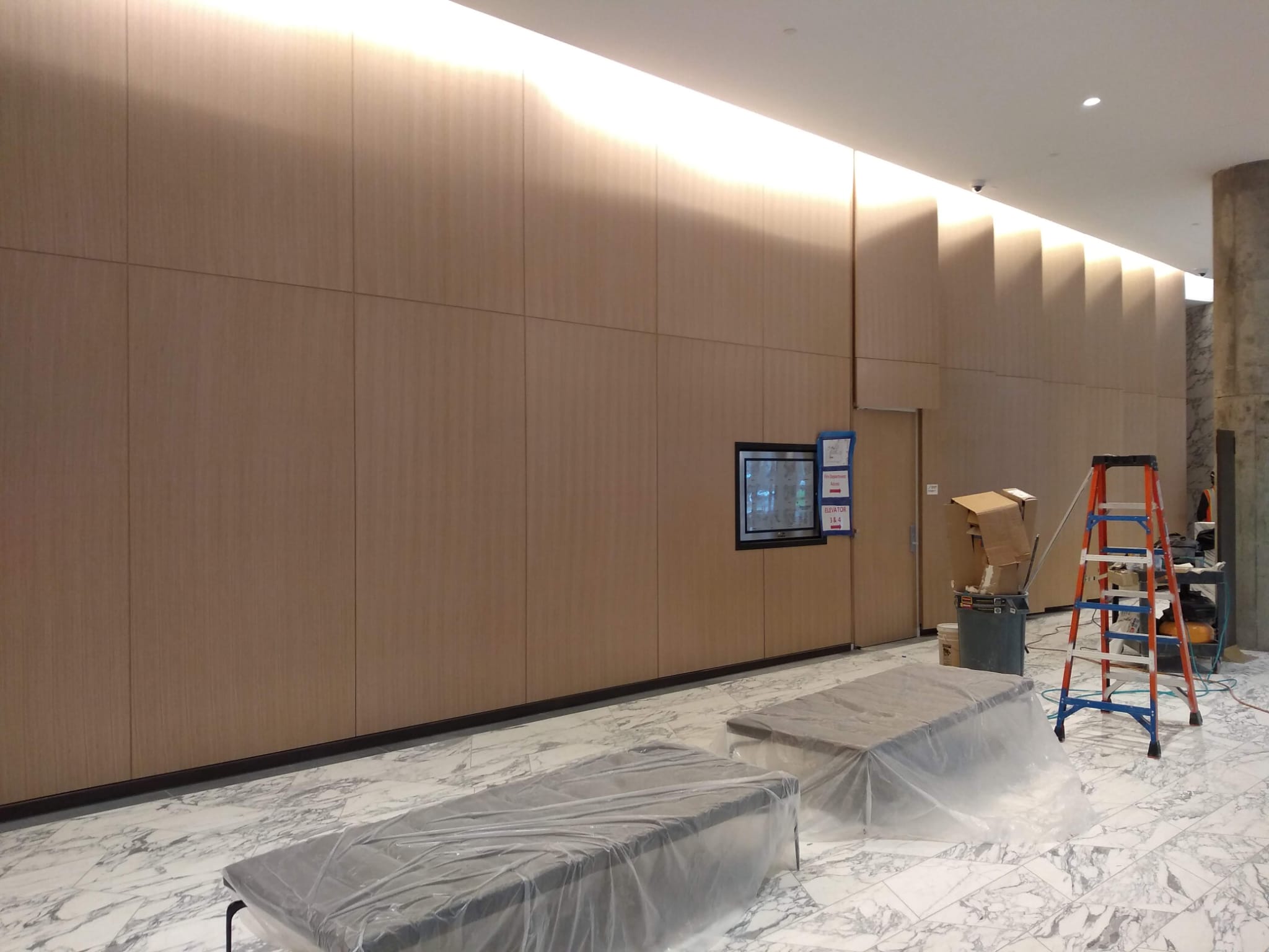 Full-scale architectural blonde oak wall paneling and indirect ceiling illumination over marble flooring in Winston-Salem NC