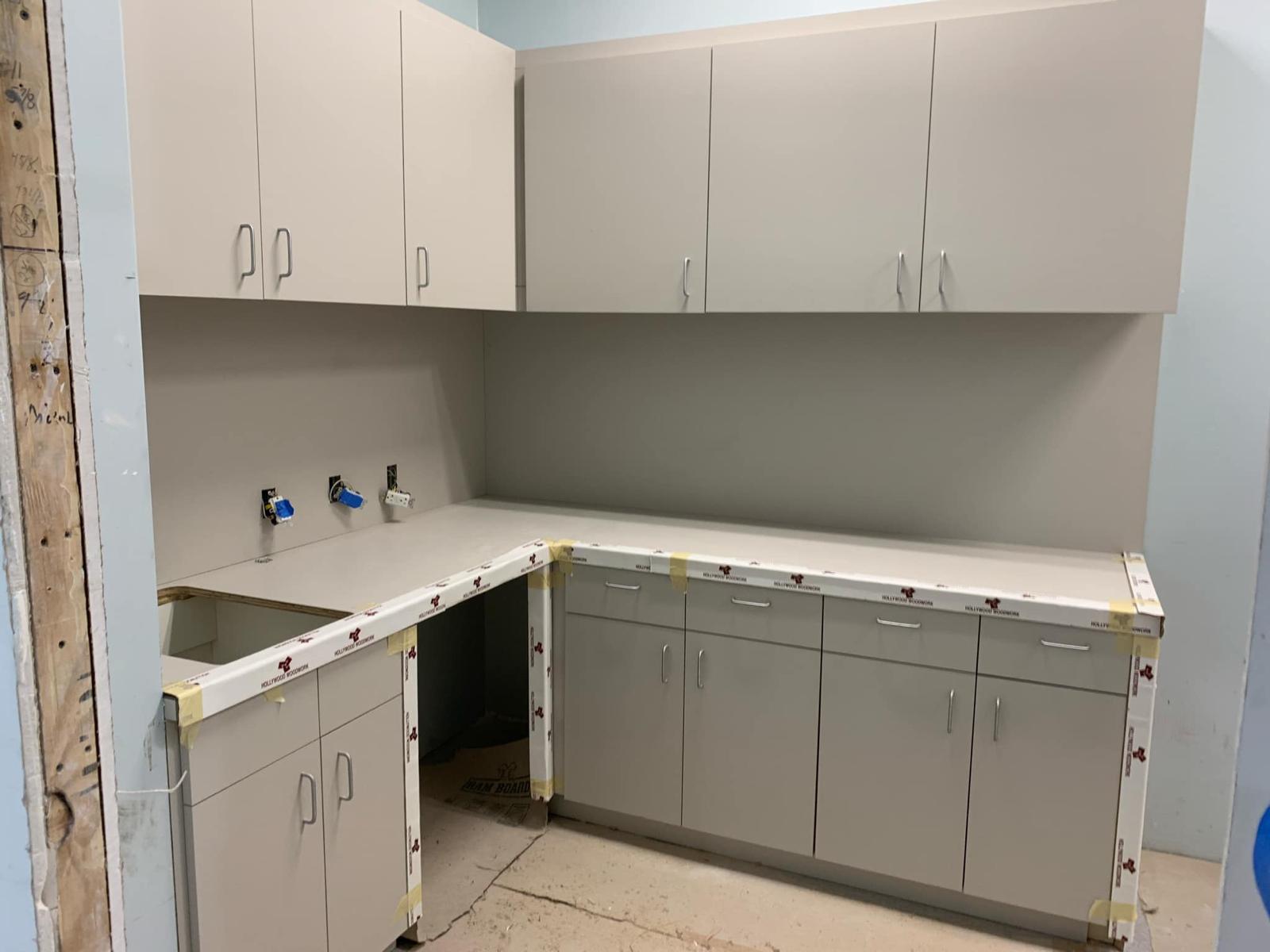 L-shaped commercial breakroom cabinetry with sink cutout and upper storage units in Lewisville NC
