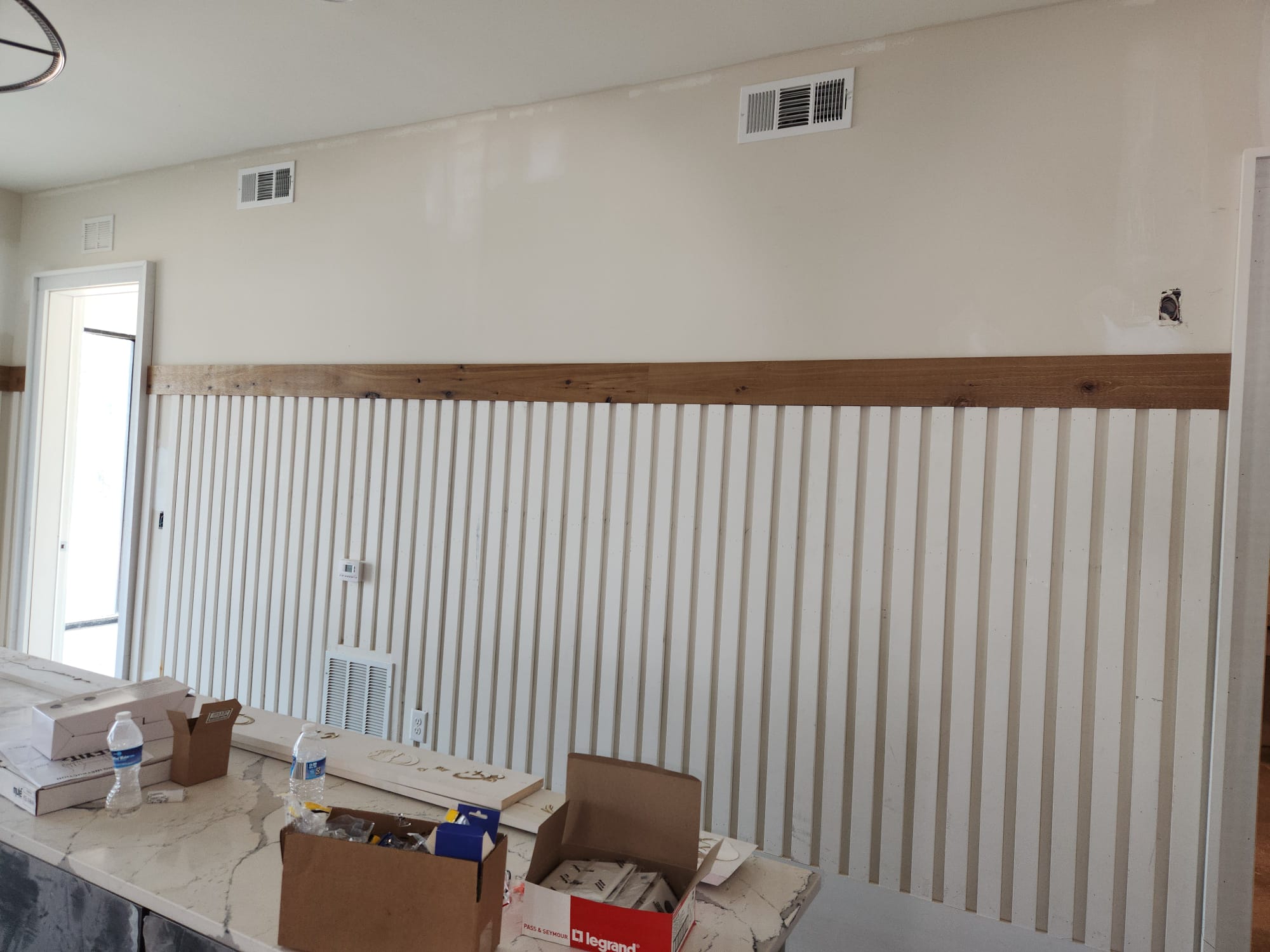 White vertical slat wainscoting accent wall with stained oak cap rail installed in Clemmons NC