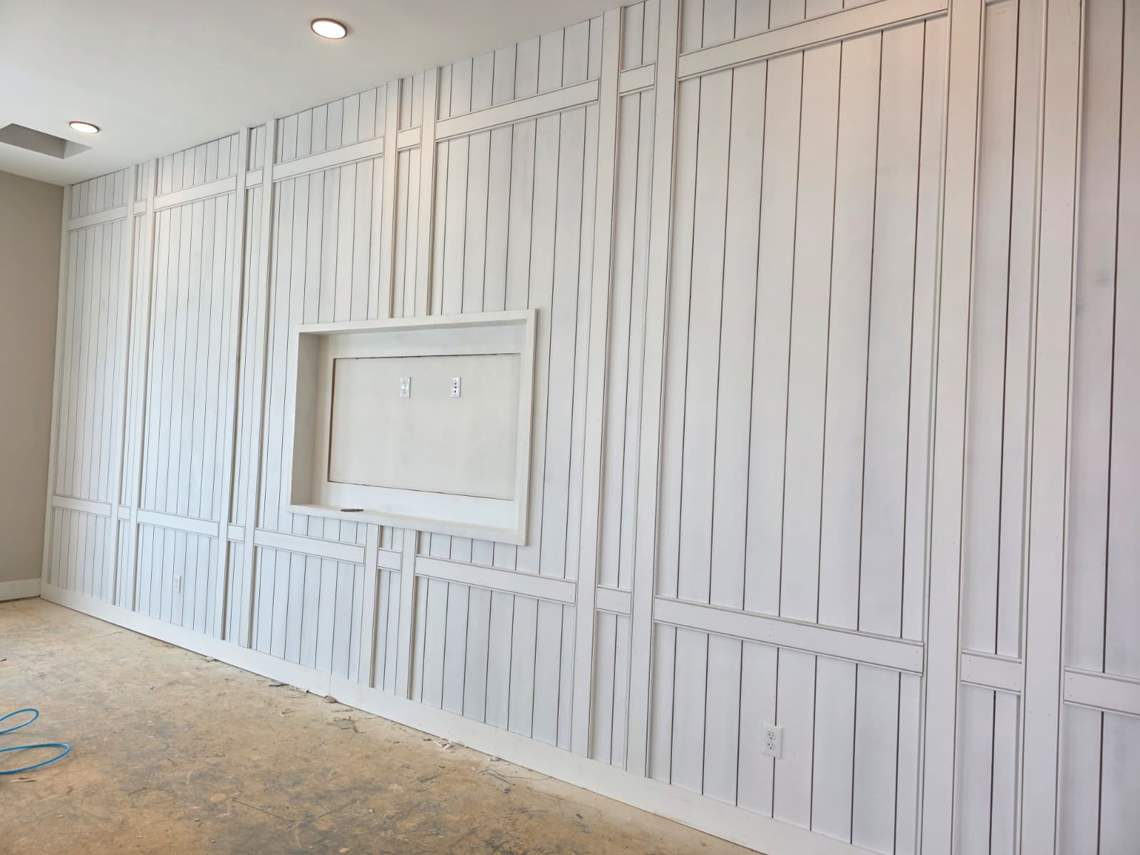 Full-wall custom vertical board and batten paneling with built-in recessed TV mount niche in Winston-Salem NC