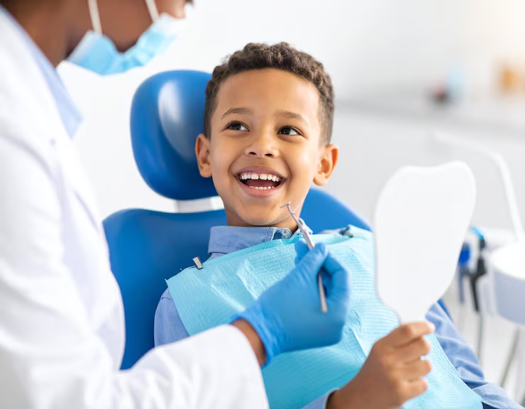 Niño feliz en consulta de odontopediatría mirando su sonrisa en el espejo