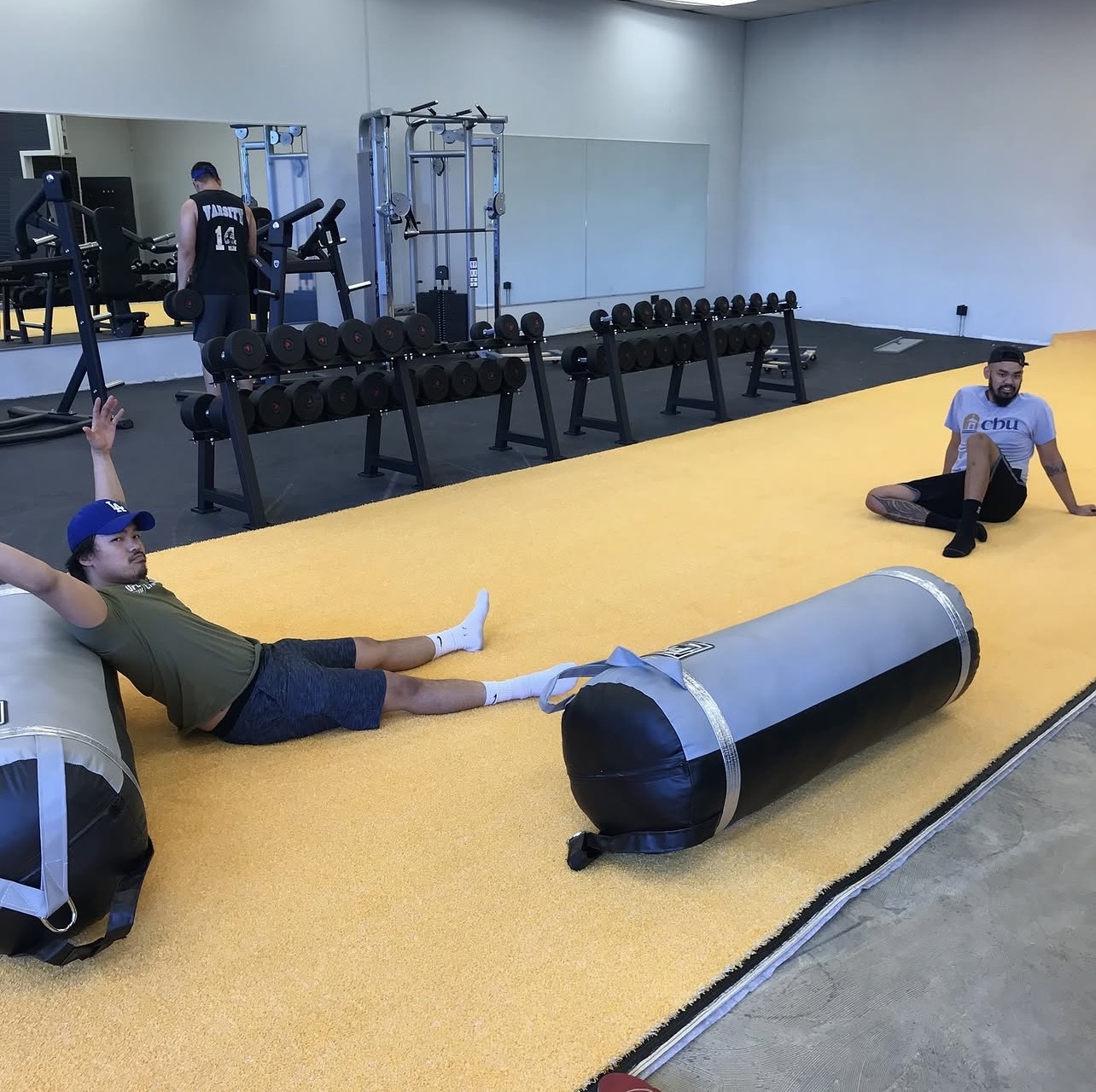 Chris and Erickson training on foam rollers in the early gym setup with yellow flooring