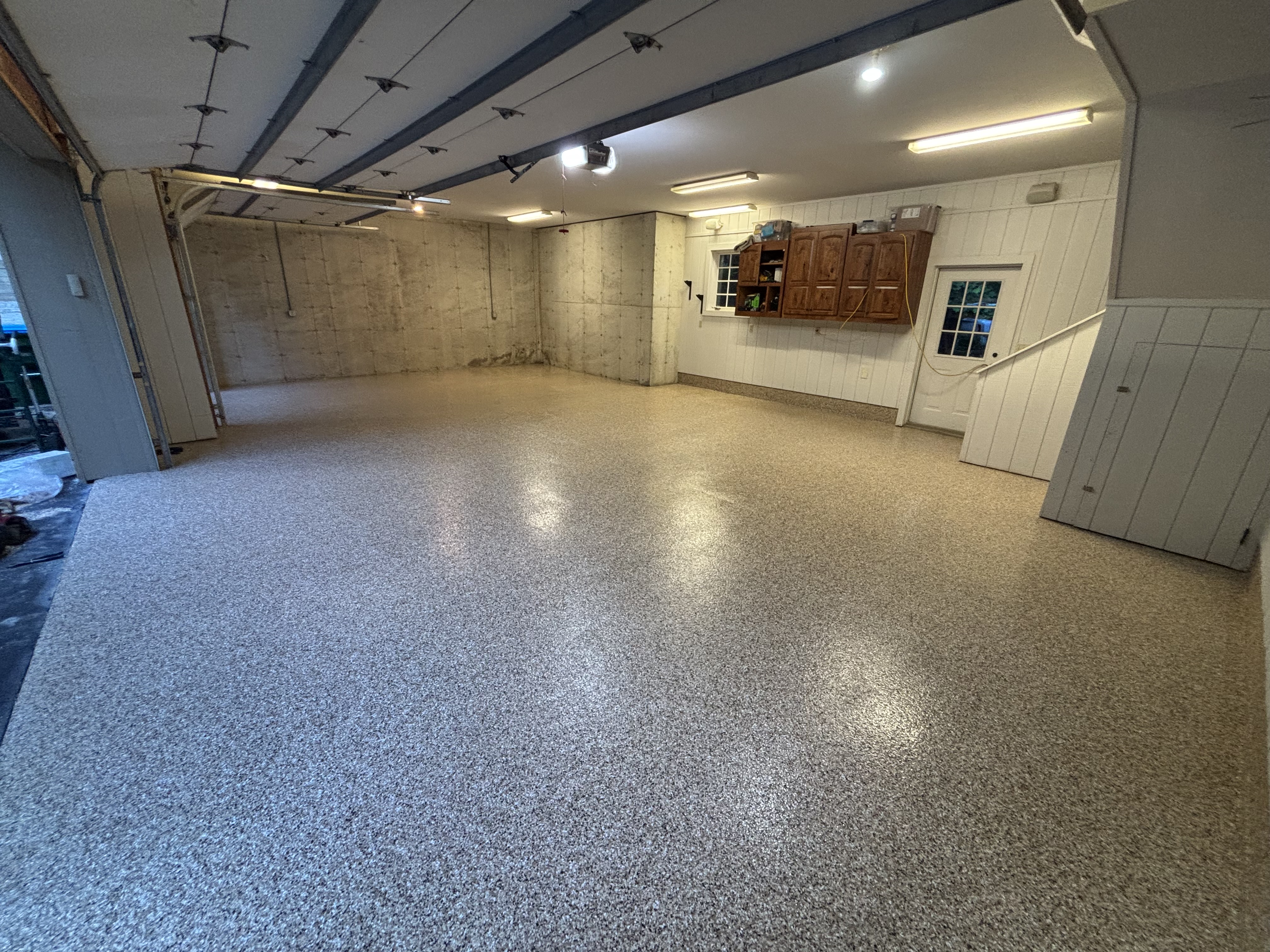 Deep multi-car finished garage floor with warm flake blend and architectural lighting