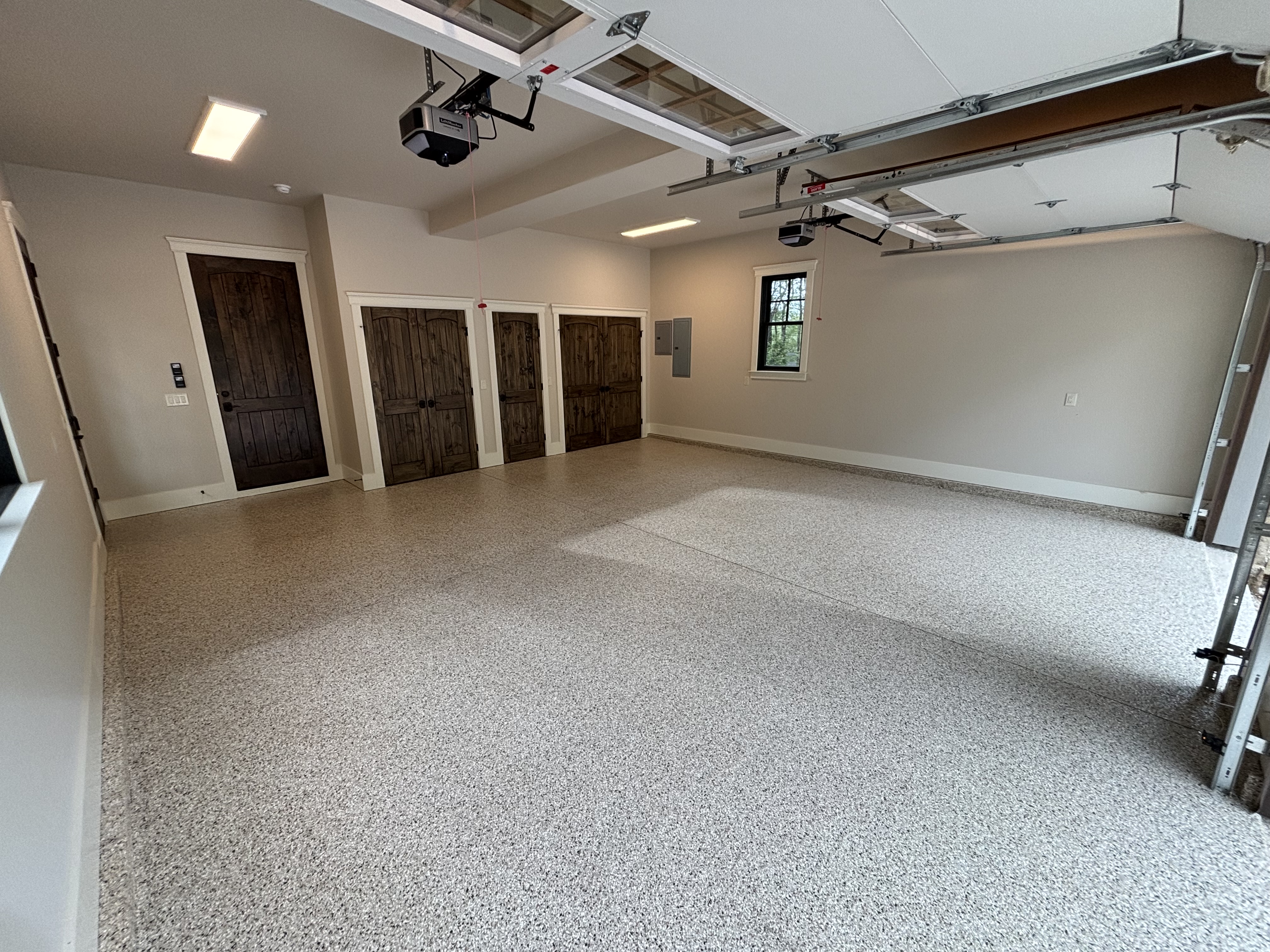 Spacious multi-bay garage with finished full-broadcast flake floor and wood carriage doors