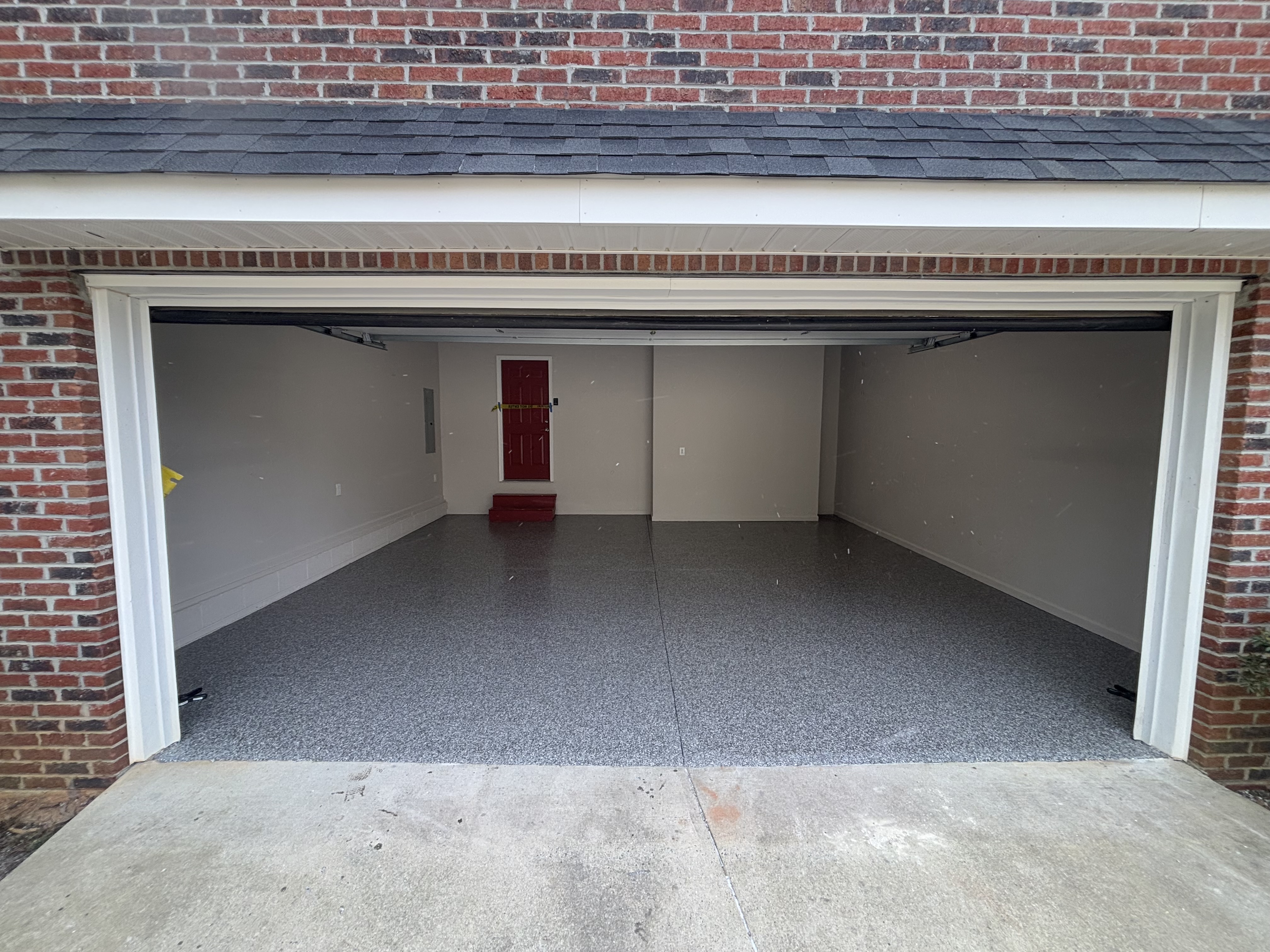 Exterior brick home garage entrance showing seamless dark flake floor finish