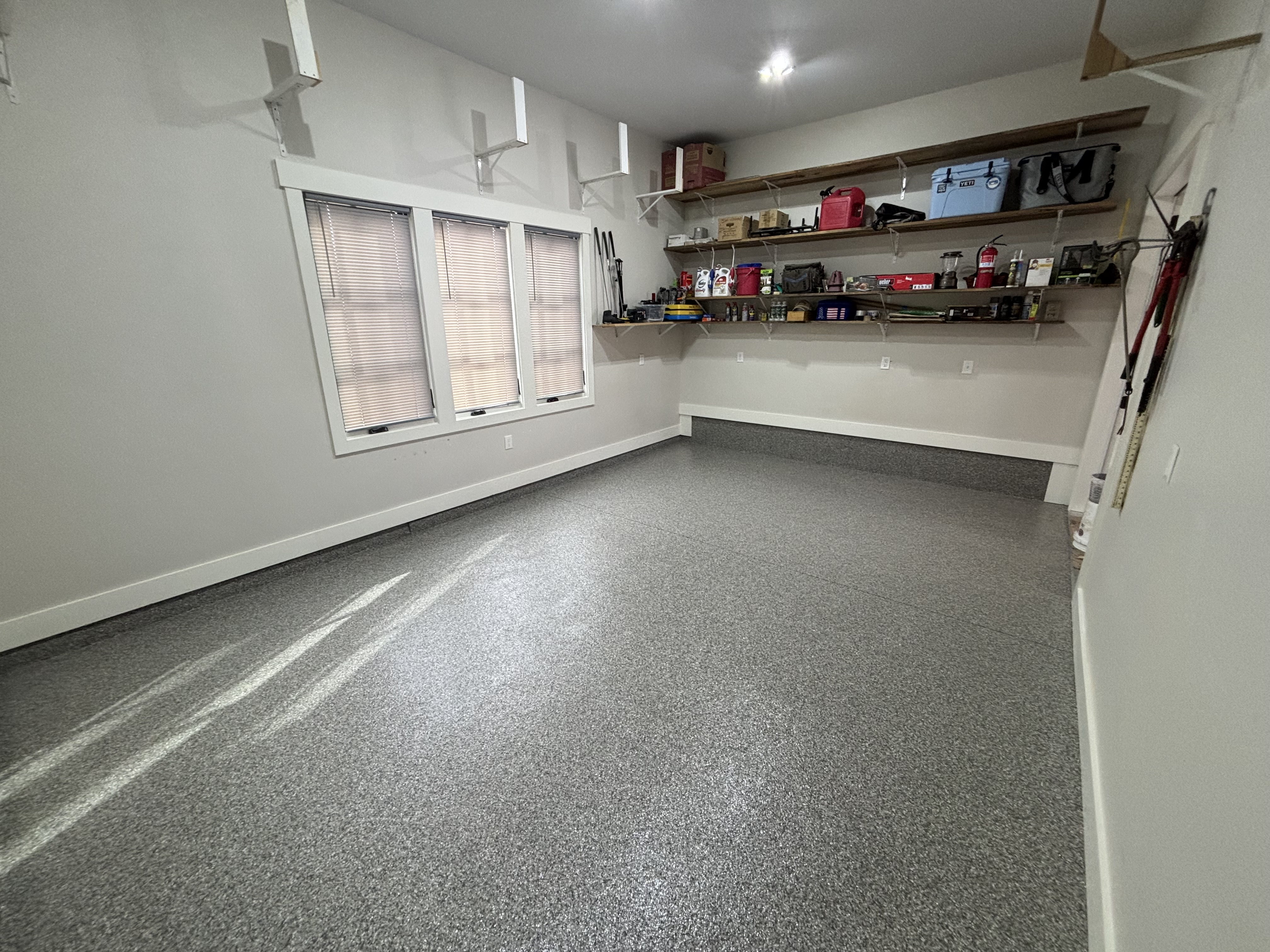 Clean organized garage interior featuring high-gloss seamless flake flooring and storage