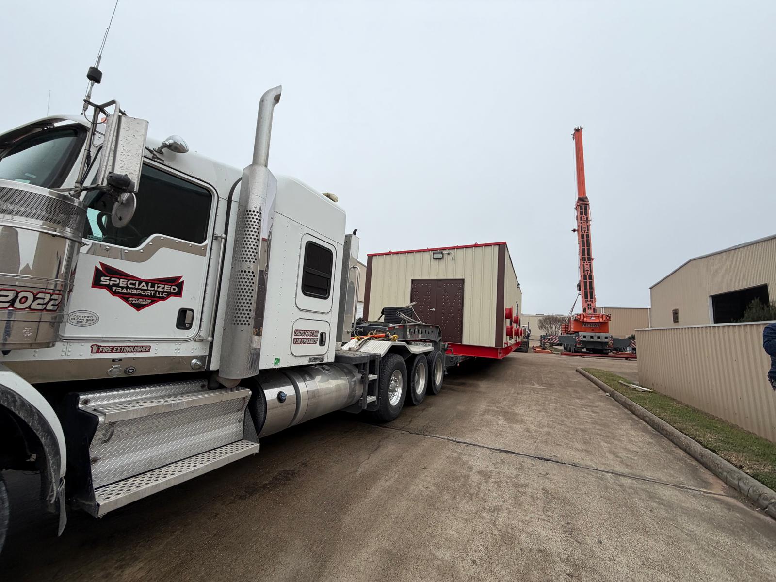 Specialized Transport truck hauling modular building with logo on door