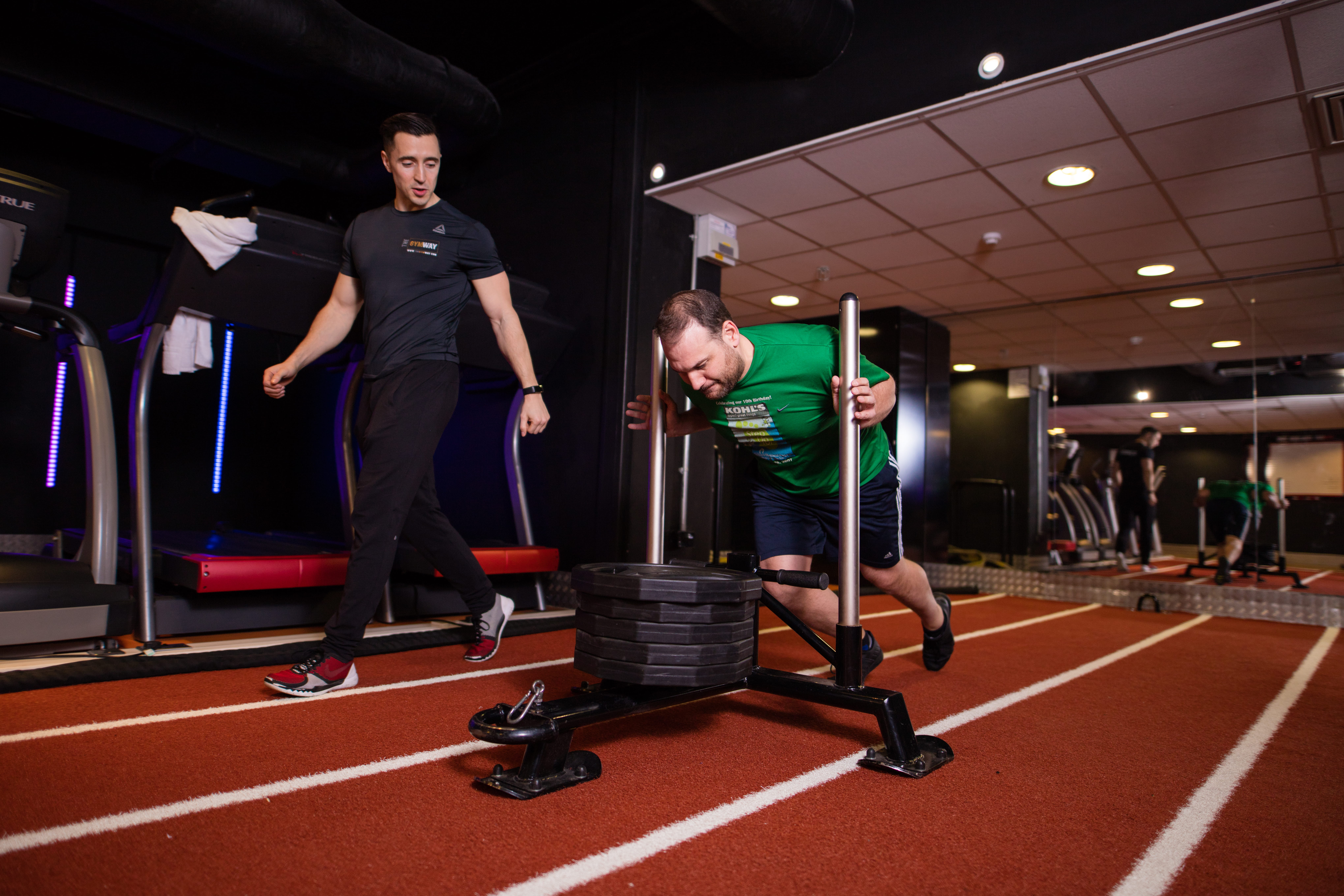 Fabio Bonanno coaching a client pushing a weighted sled on the gym track