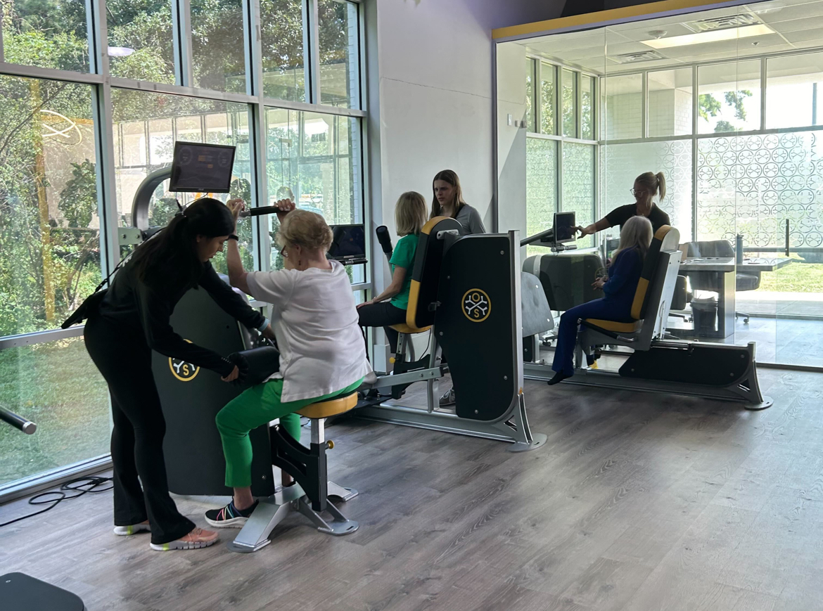 OsteoStrong members and coaches working together on equipment during a session