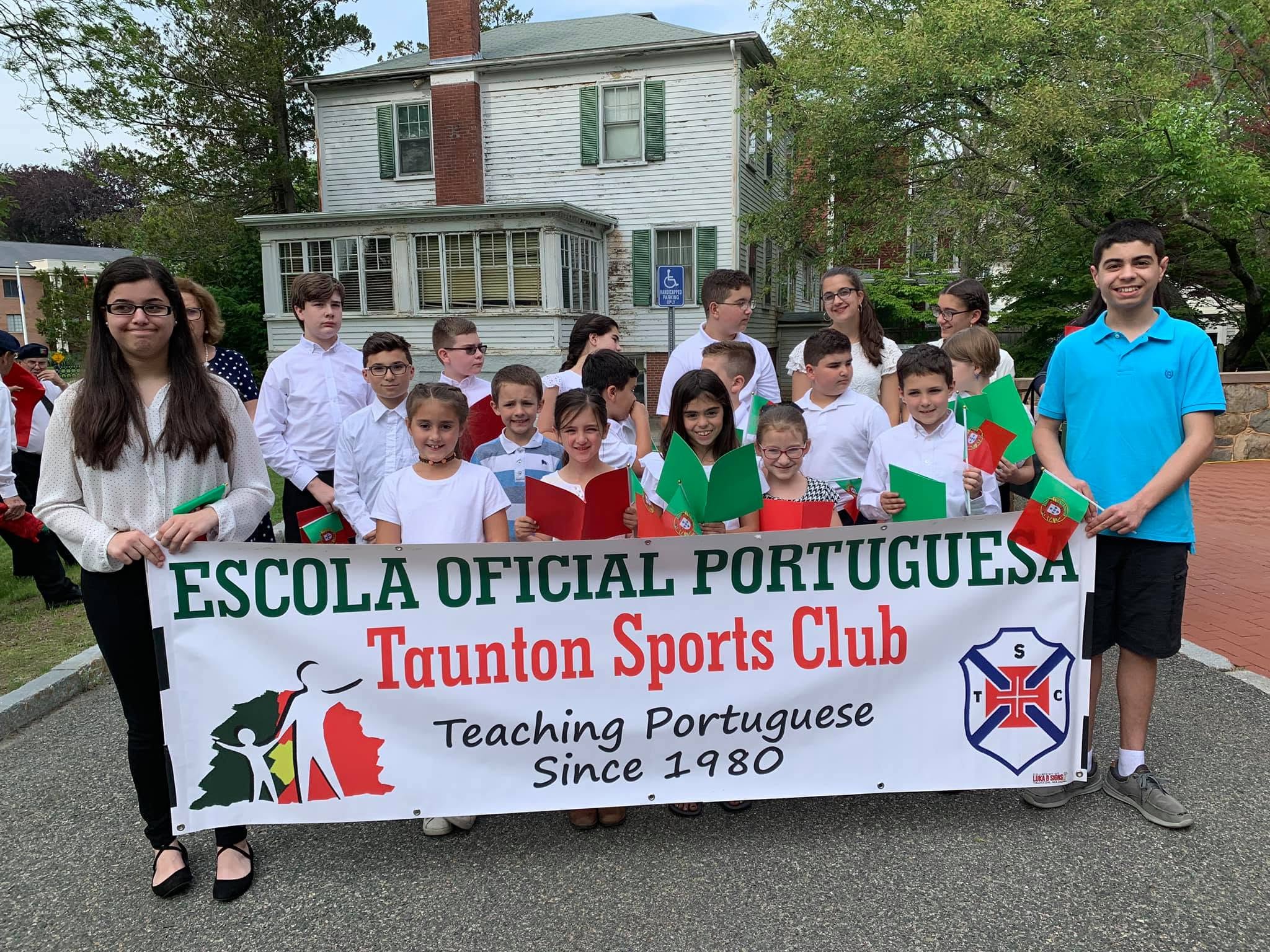 Students and teachers of Escola Oficial Portuguesa - Taunton Sports Club holding banner teaching Portuguese since 1980