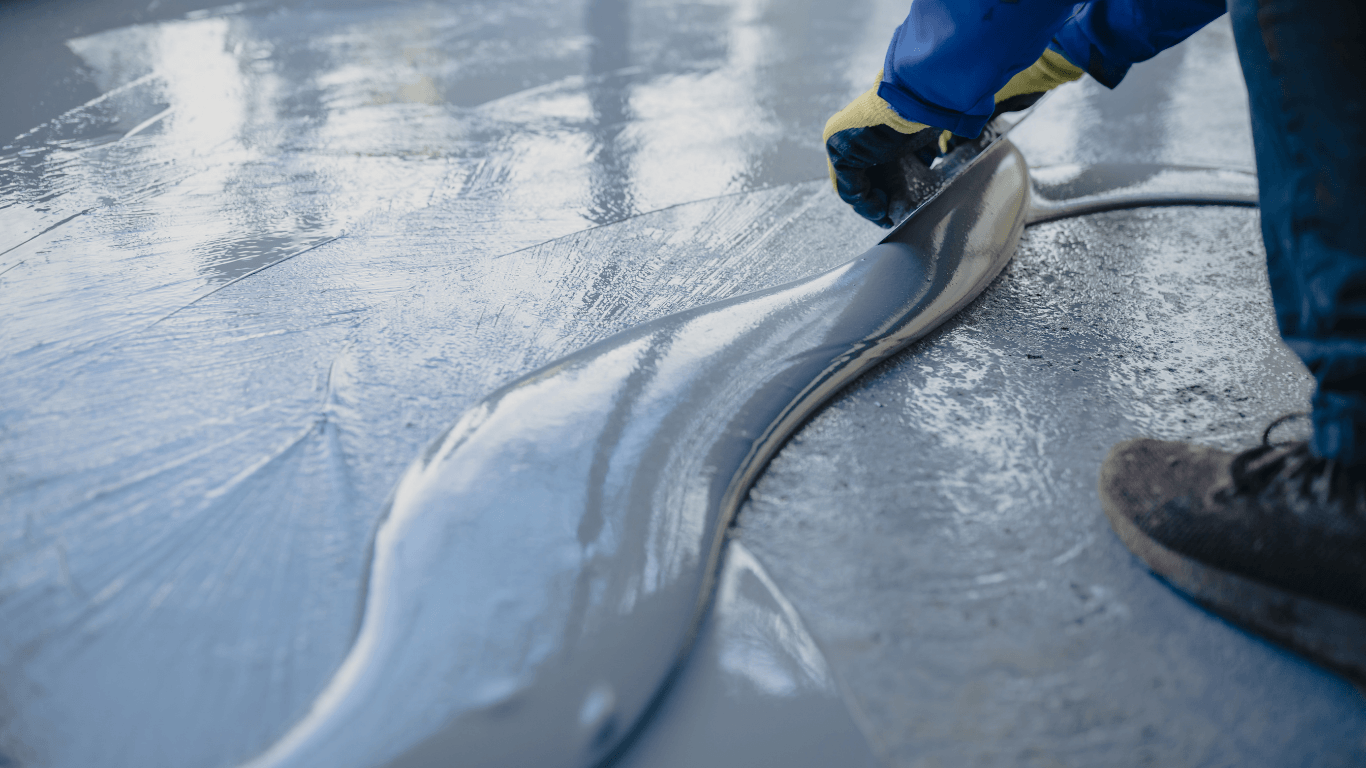 Close-up of a trowel spreading fresh epoxy over a repaired and prepared concrete surface during an epoxy floor repair and recoat in Glendale, AZ