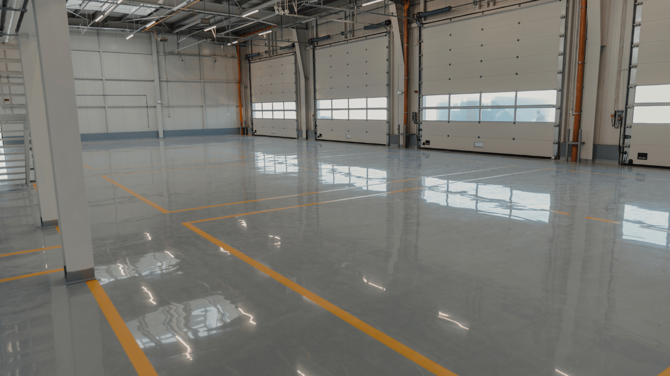 Glossy, seamless epoxy garage and commercial floor reflecting overhead light after a garage flooring epoxy coating installation in Glendale, AZ