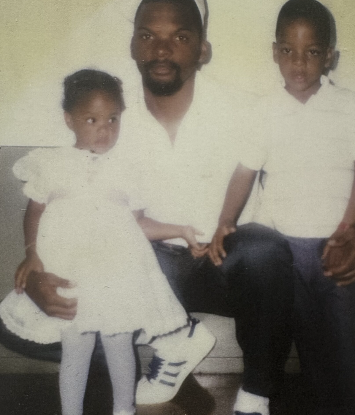 Faded color photograph of man seated with two young children
