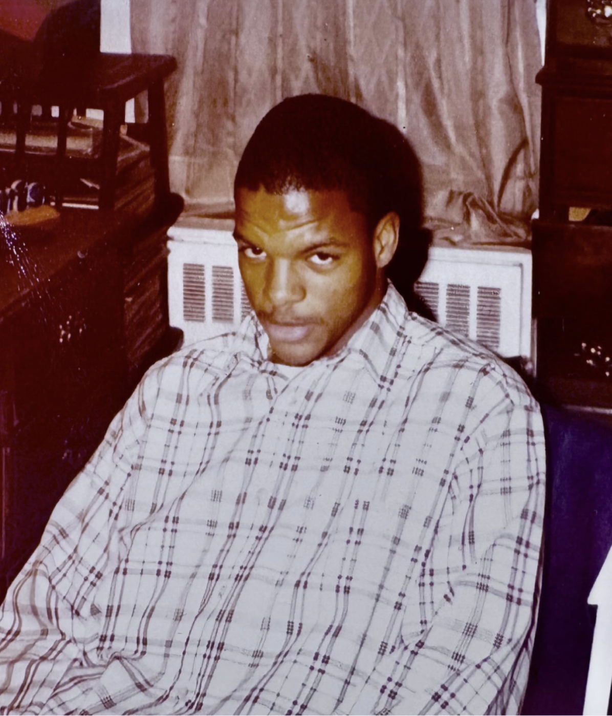Young man in plaid button-up shirt seated indoors