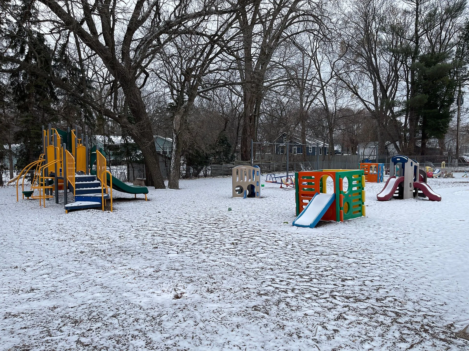 Large fenced playground area with age-specific play structures and winter scenery