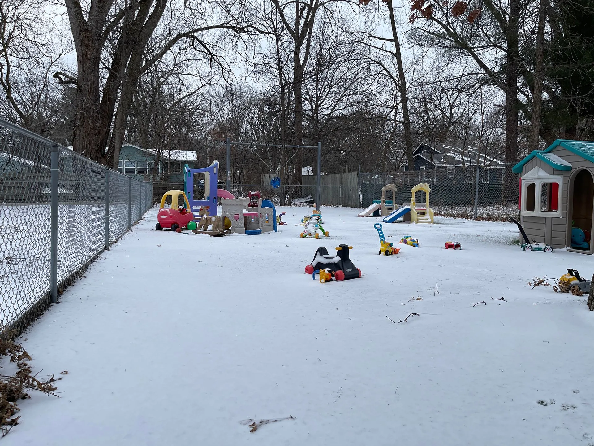 Dedicated enclosed play yard with ride-on toys, playhouses, and slides