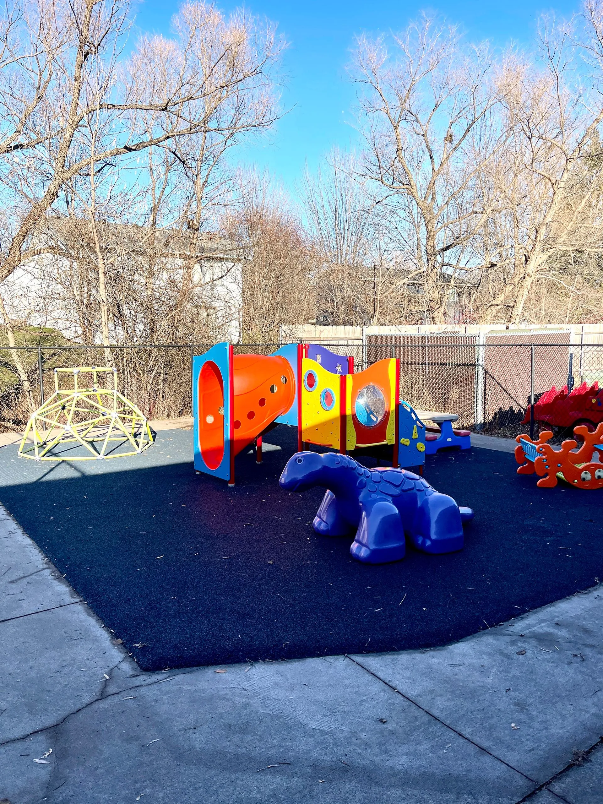 Outdoor playground featuring crawl tunnels, slide play structures, and safety turf