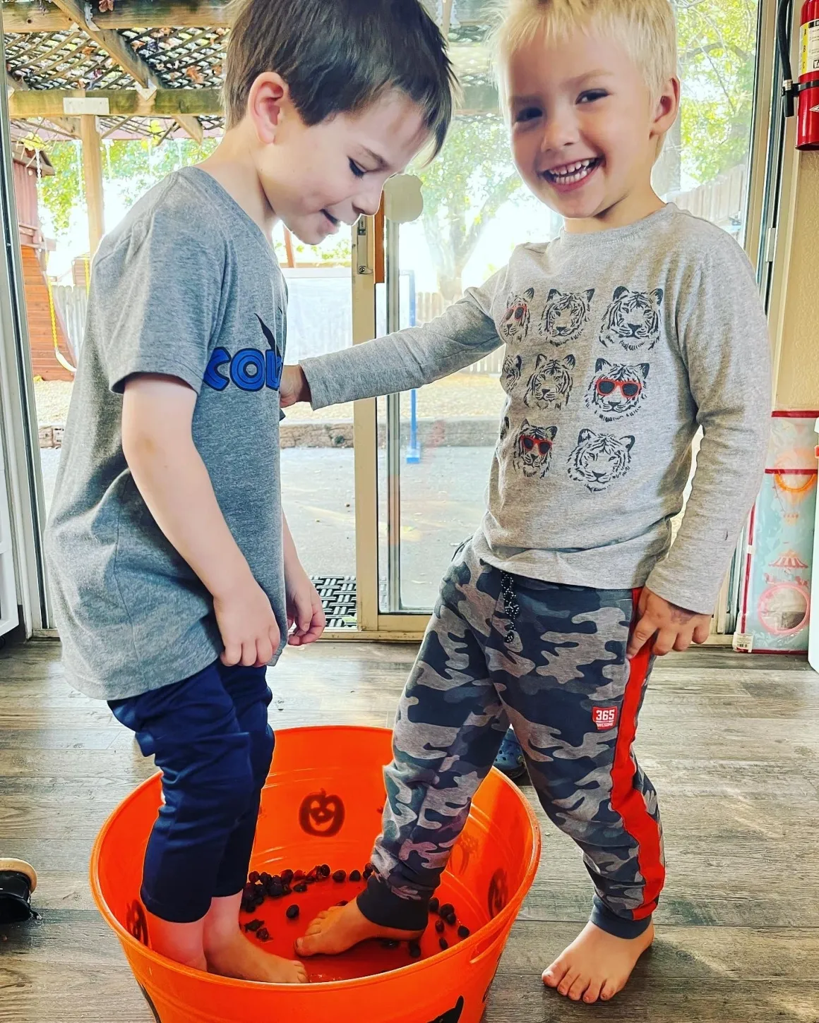 Smiling boys enjoying tactile sensory tub foot exploration together