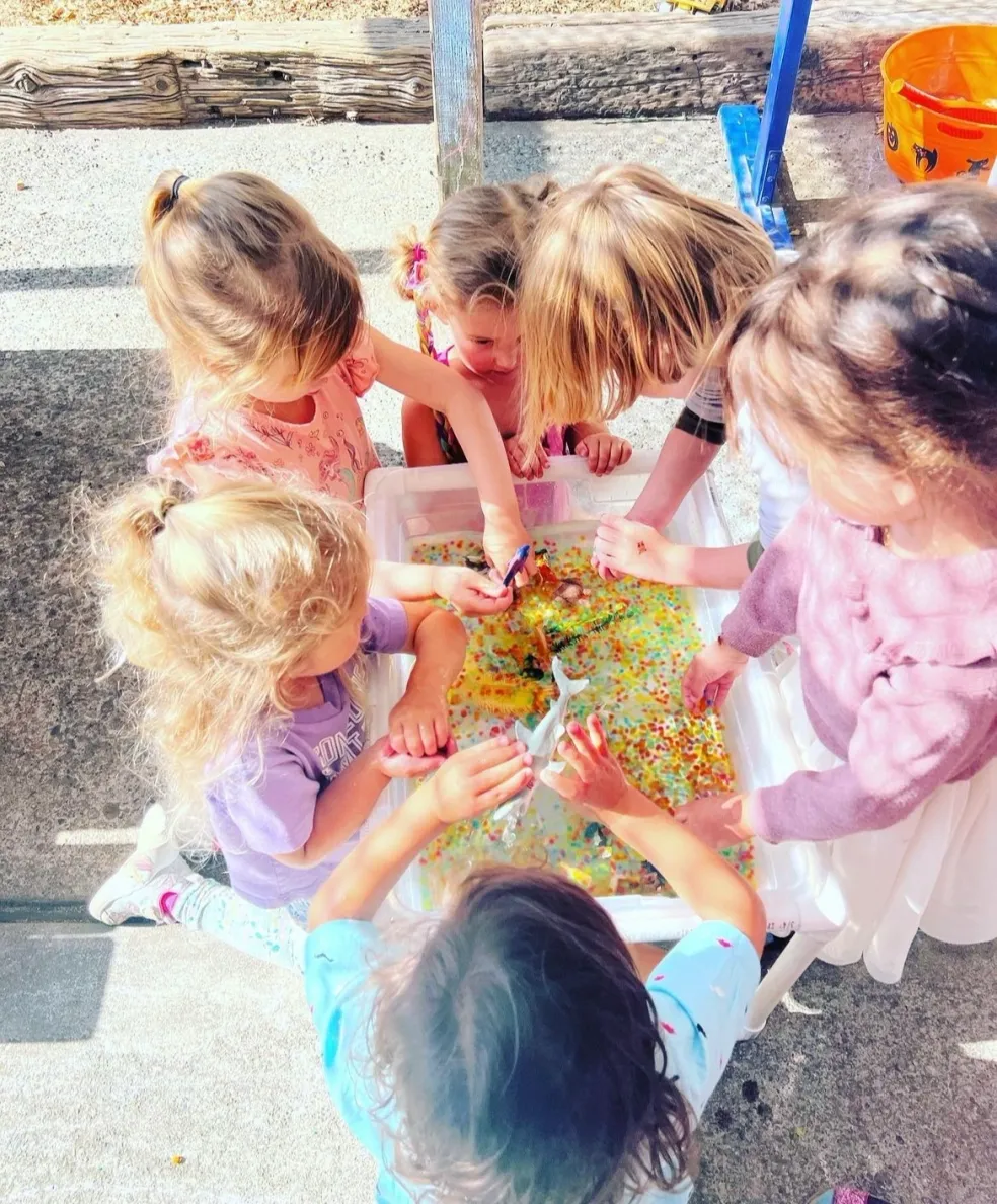 Children exploring water beads and ocean toys at the outdoor sensory water table
