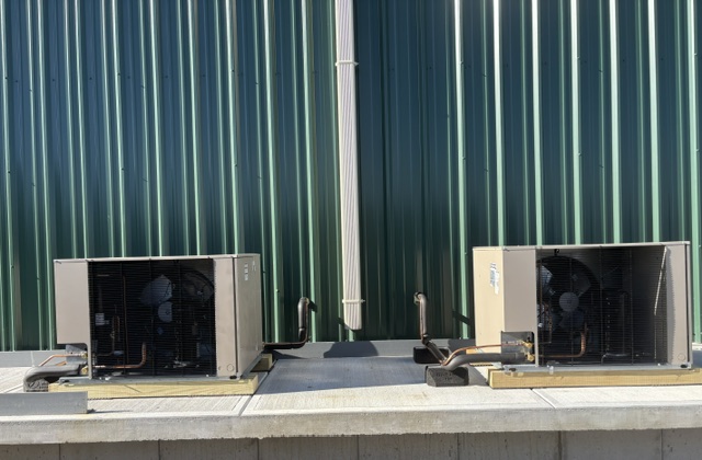 Commercial outdoor condensing units installed on concrete pad outside facility