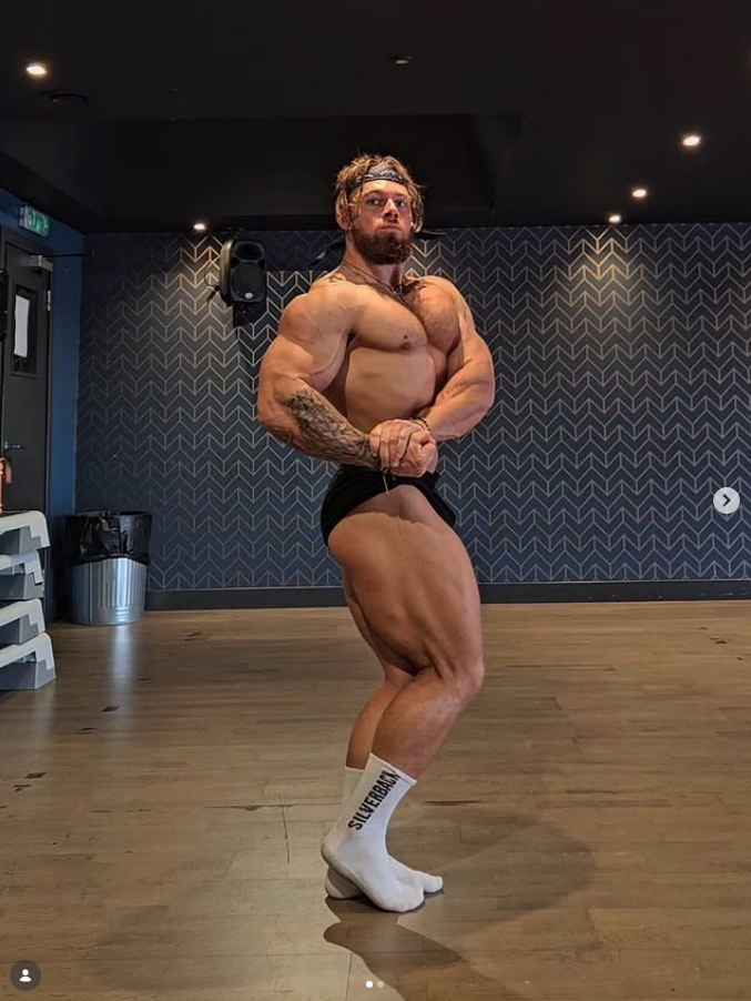 James Alabaster side chest physique pose in gym studio