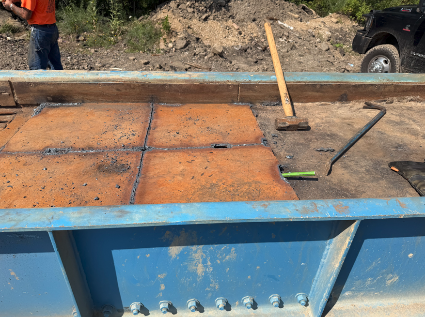Replacement wear plates welded into the floor of a steel dump body