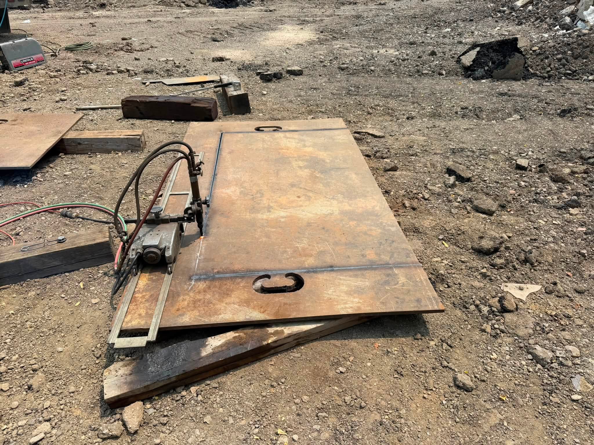 Oxy-fuel track torch cutting a rectangular opening in steel plate on site