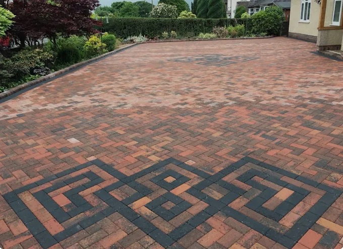 Large red block paving driveway with custom inlaid charcoal geometric motifs and decorative patterns