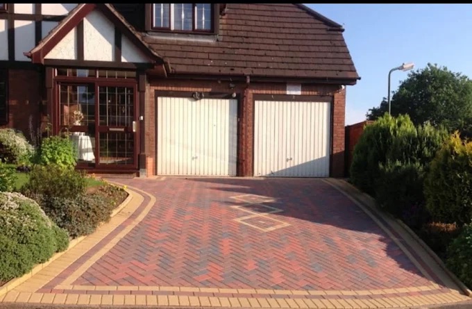 Double garage herringbone block paving driveway with inset diamond patterns and buff border