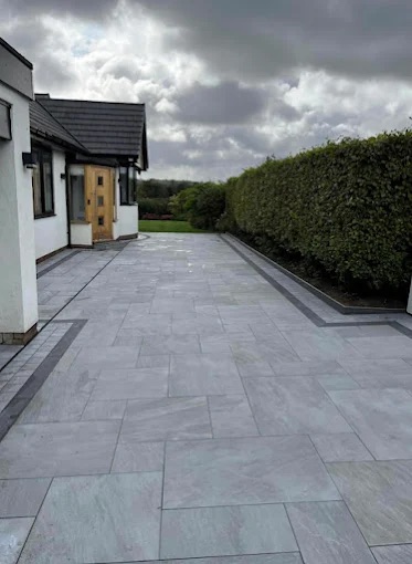 Full light grey porcelain paved residential driveway and forecourt along mature hedge border