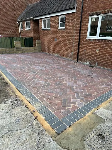 Freshly installed herringbone block paved driveway parking bay with dark charcoal soldier border